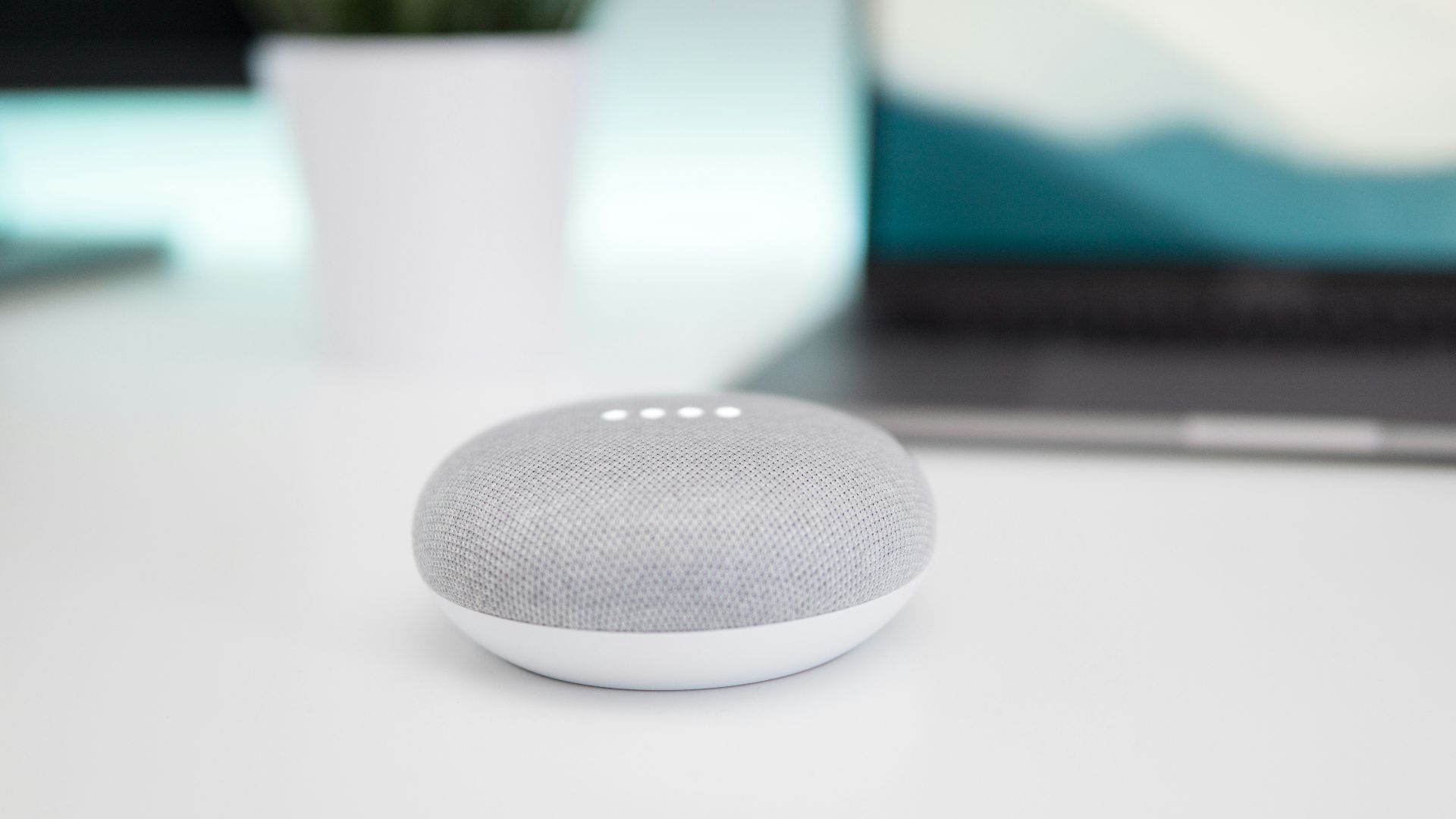 turned on gray and white Google Home Mini speaker on white surface