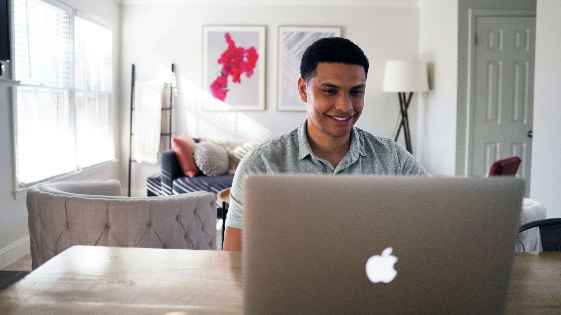 man in gray hoodie sitting on chair in front of silver macbook