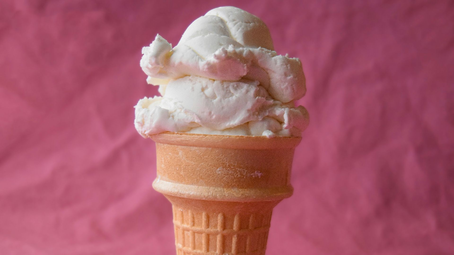 a cone of ice cream on a pink background