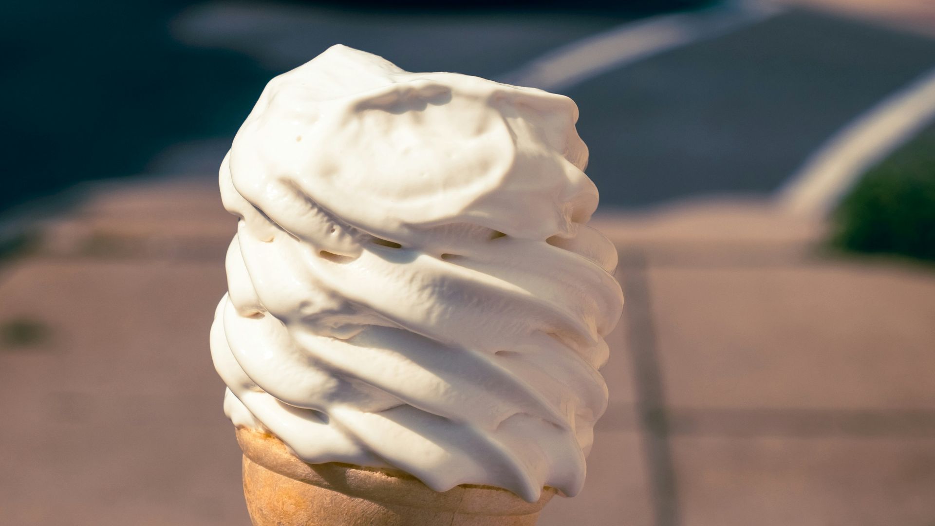 a hand holding an ice cream cone on a city street