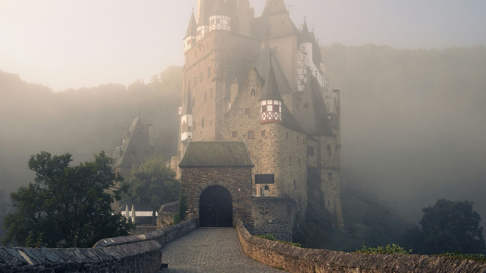 a foggy castle with a stone walkway leading to it