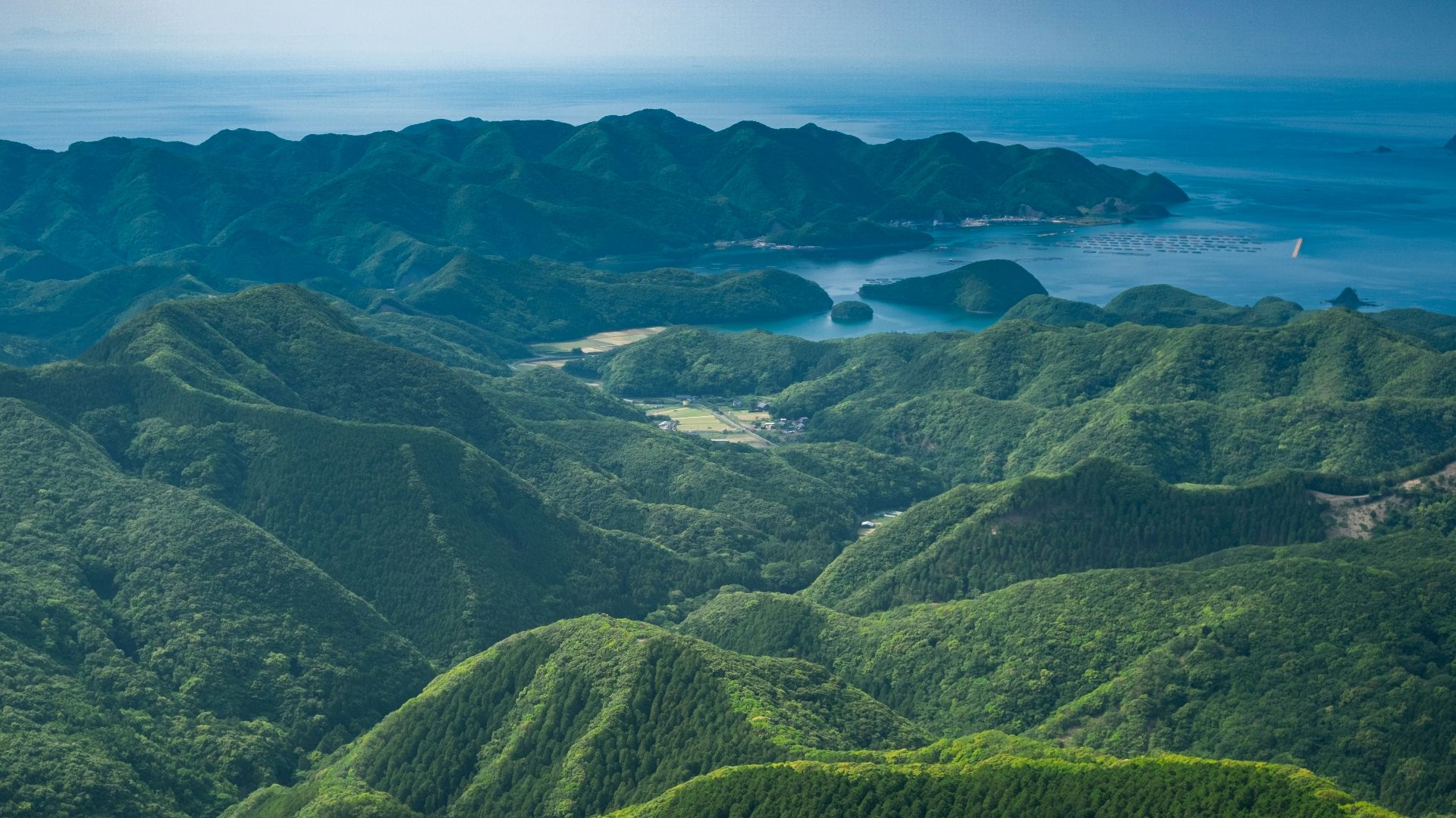 an aerial view of a mountain range with a body of water in the distance