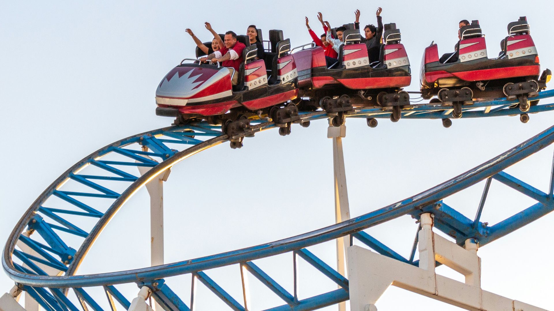 people riding red and white roller coaster during daytime