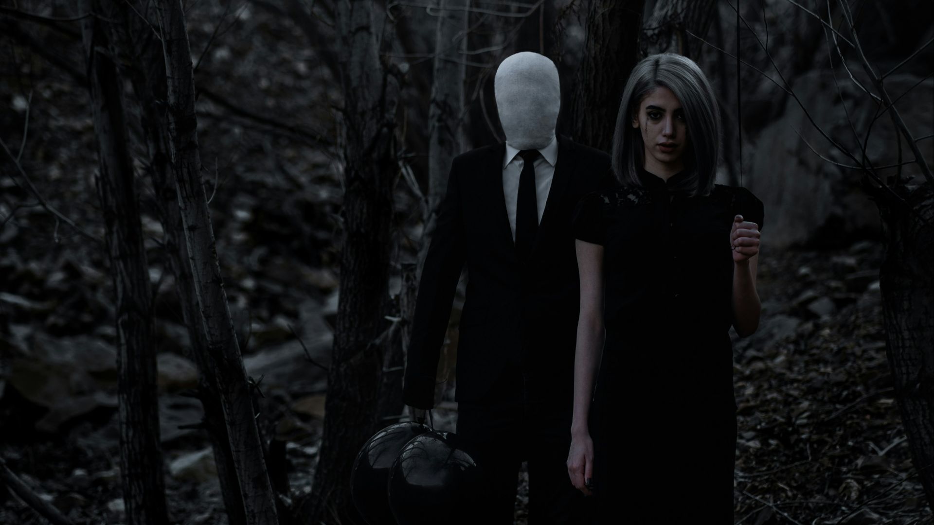 man and woman standing in the middle of forest