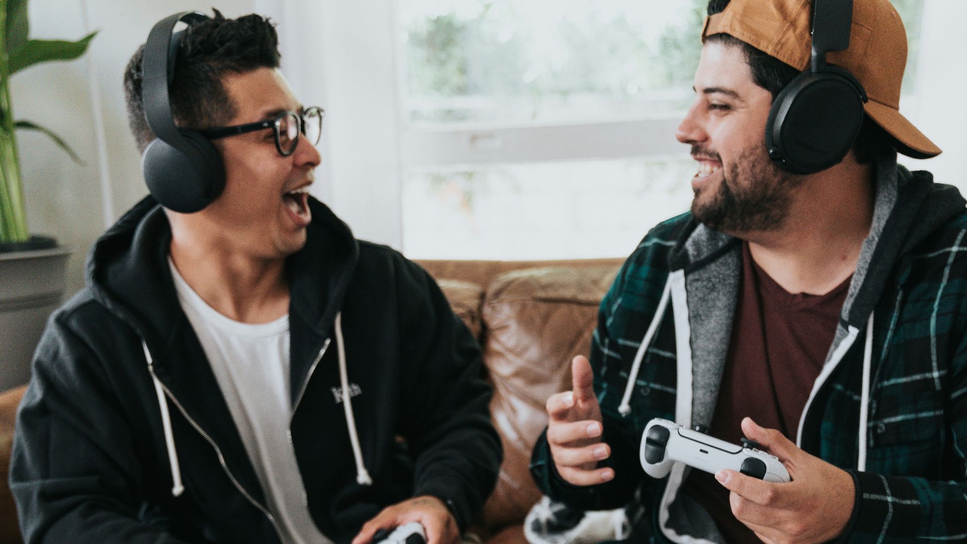 a couple of men wearing headphones and sitting on a couch