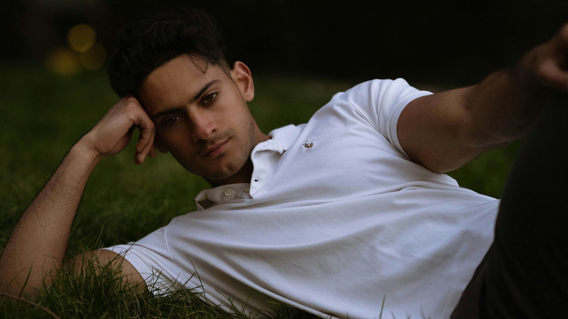 man in white polo shirt lying on green grass field