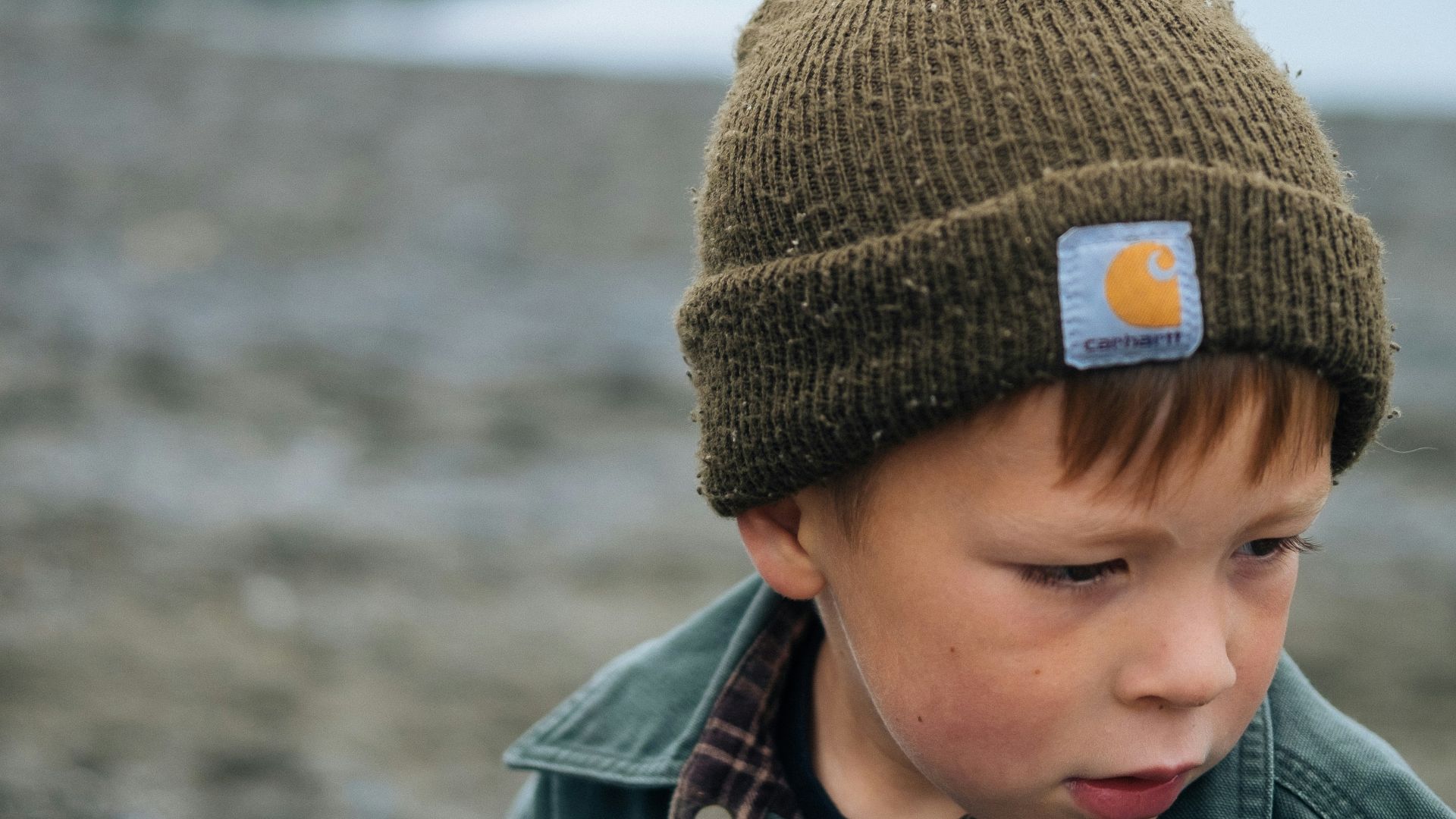 boy in brown knit cap and gray jacket