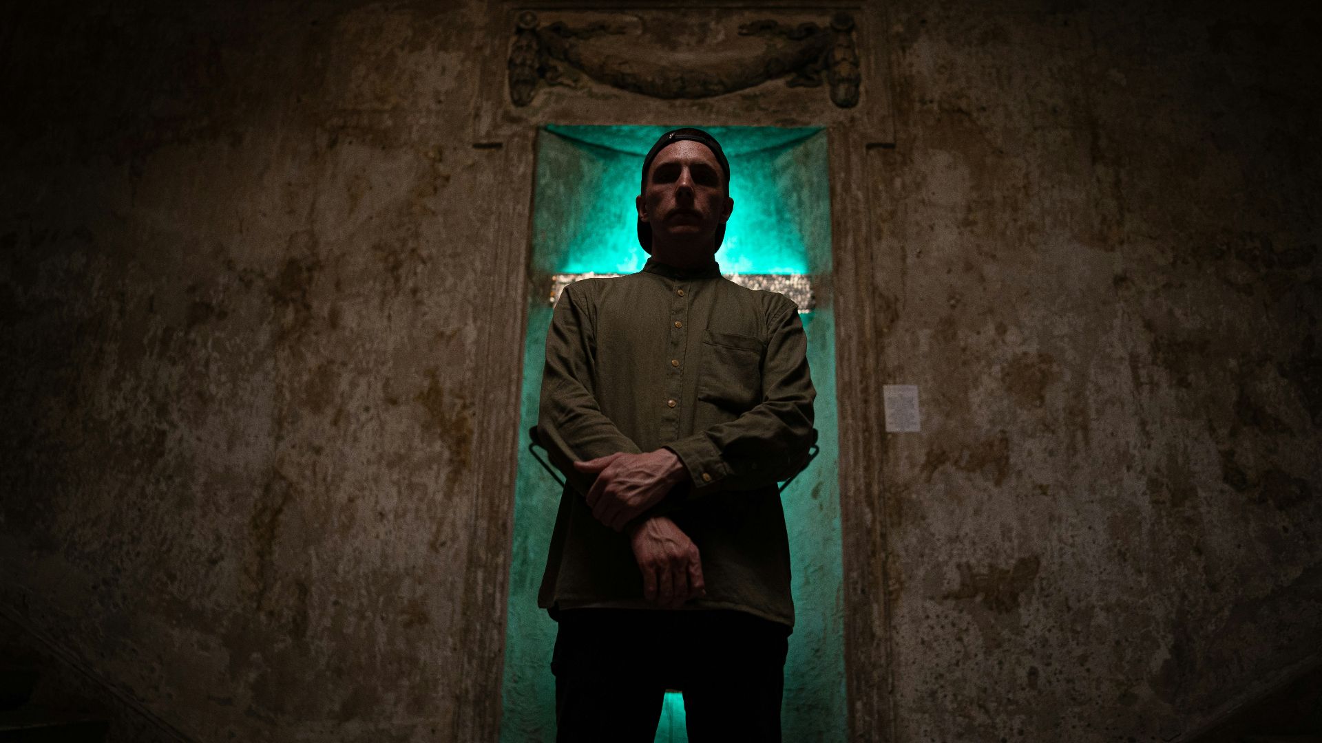 man in black jacket and black pants standing on gray concrete floor