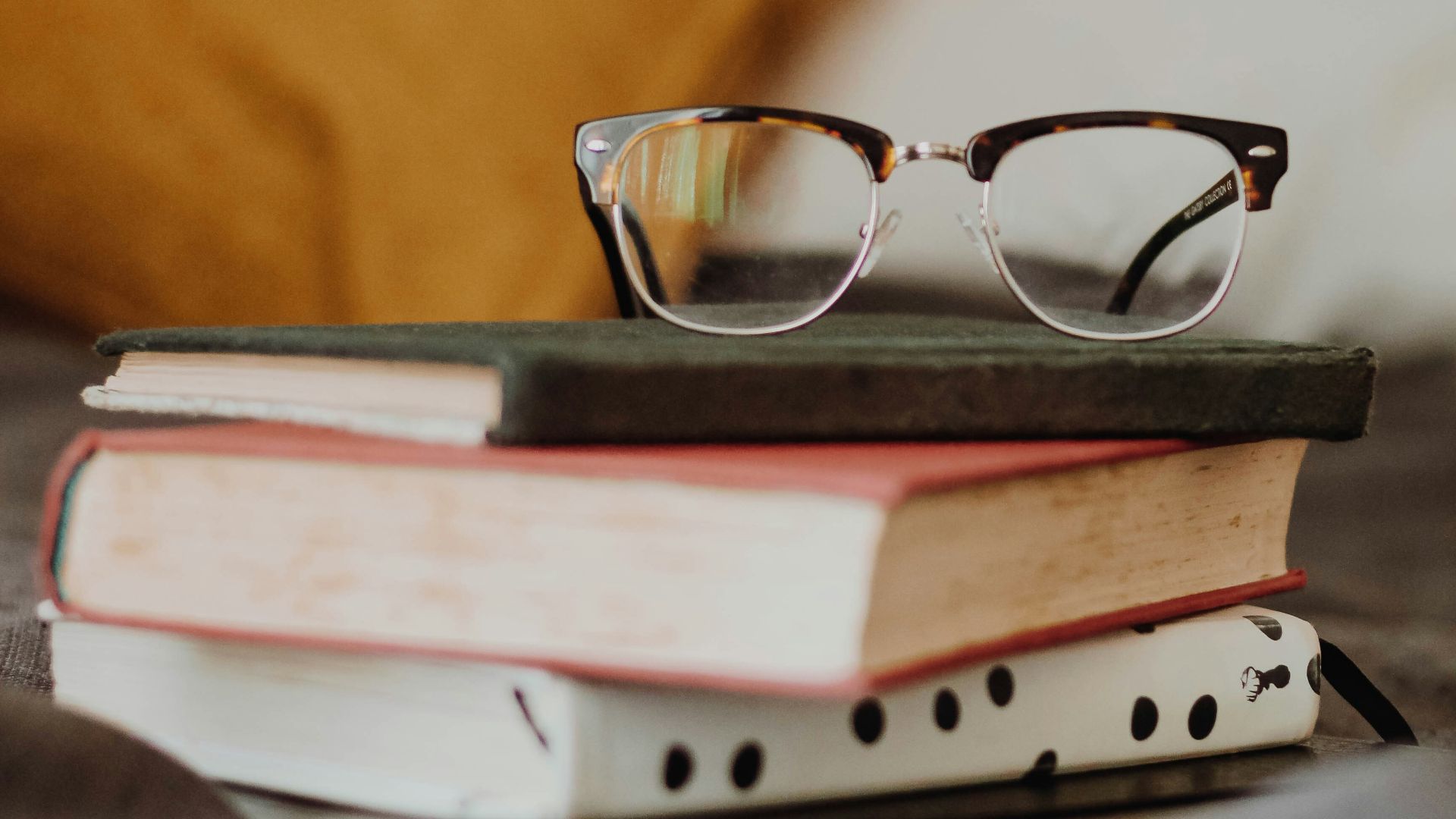 club master eyeglasses on pile of three books