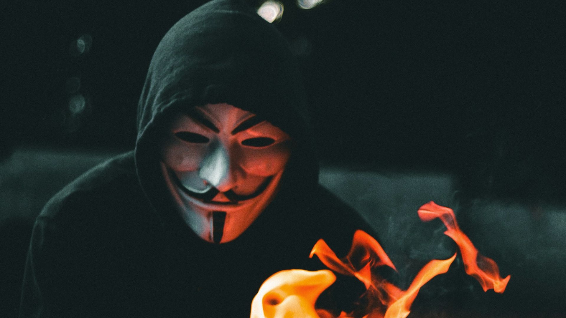 person in black hoodie with orange flame in the background