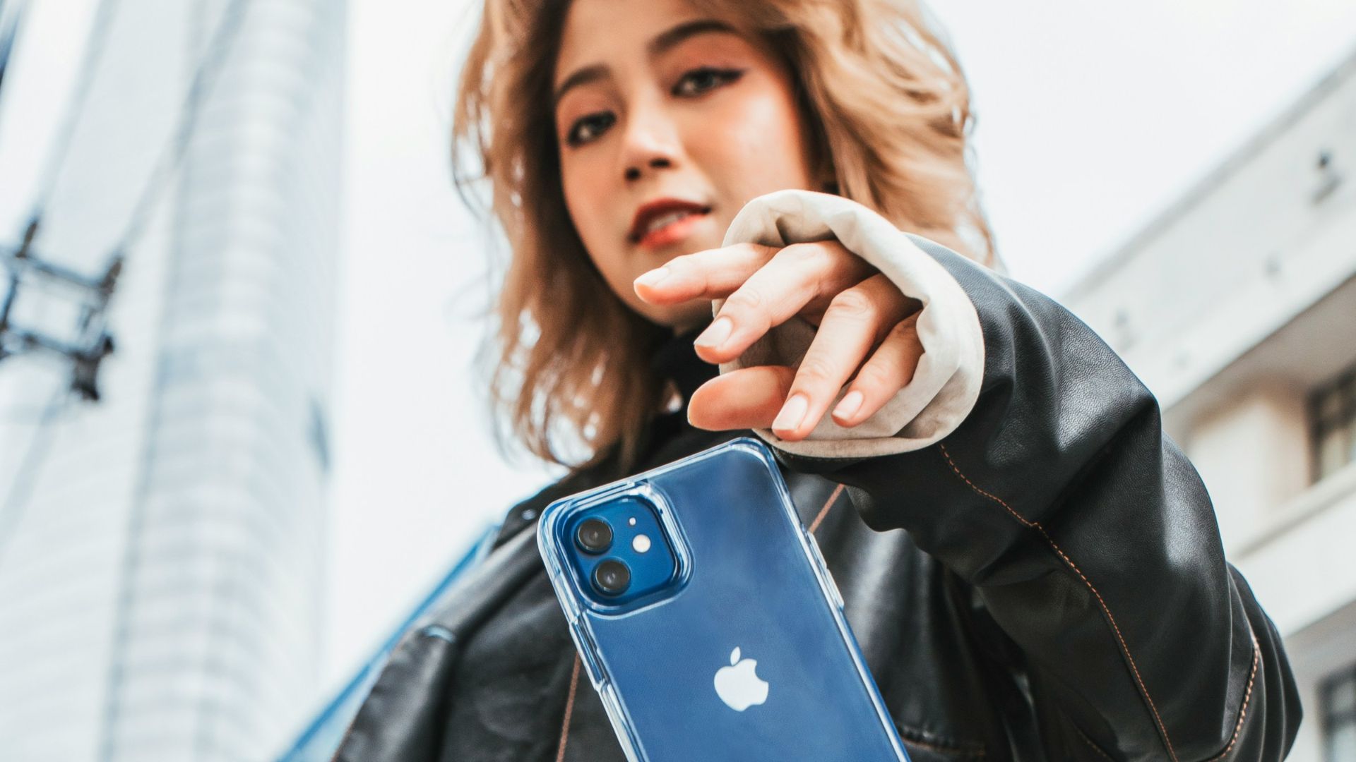 woman in black leather jacket holding blue iphone case