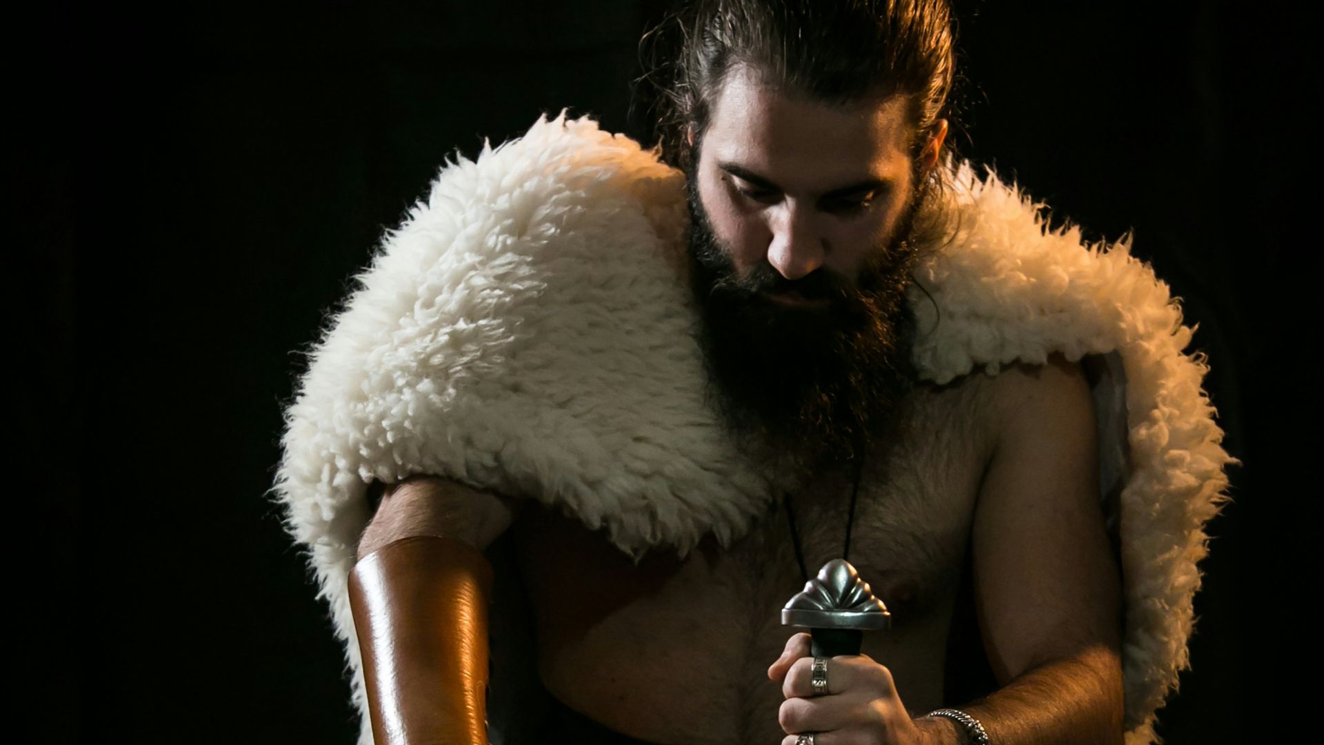 man in black pants sitting on chair holding bottle