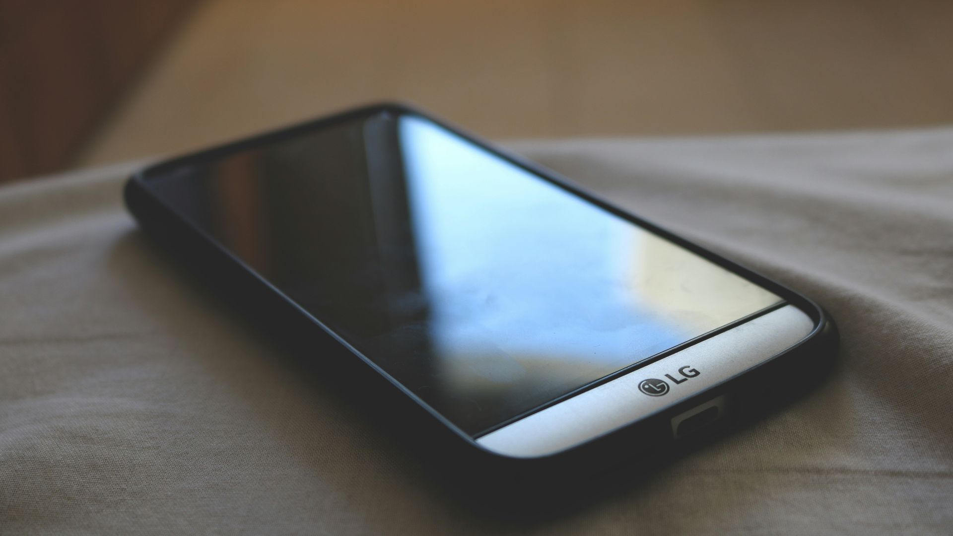 grey LG Android smartphone with black smartphone case on grey textile