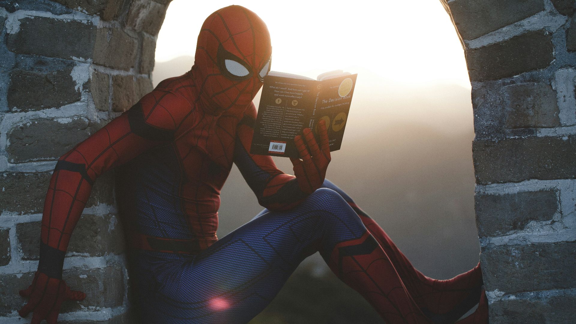 Spider-Man leaning on concrete brick while reading book