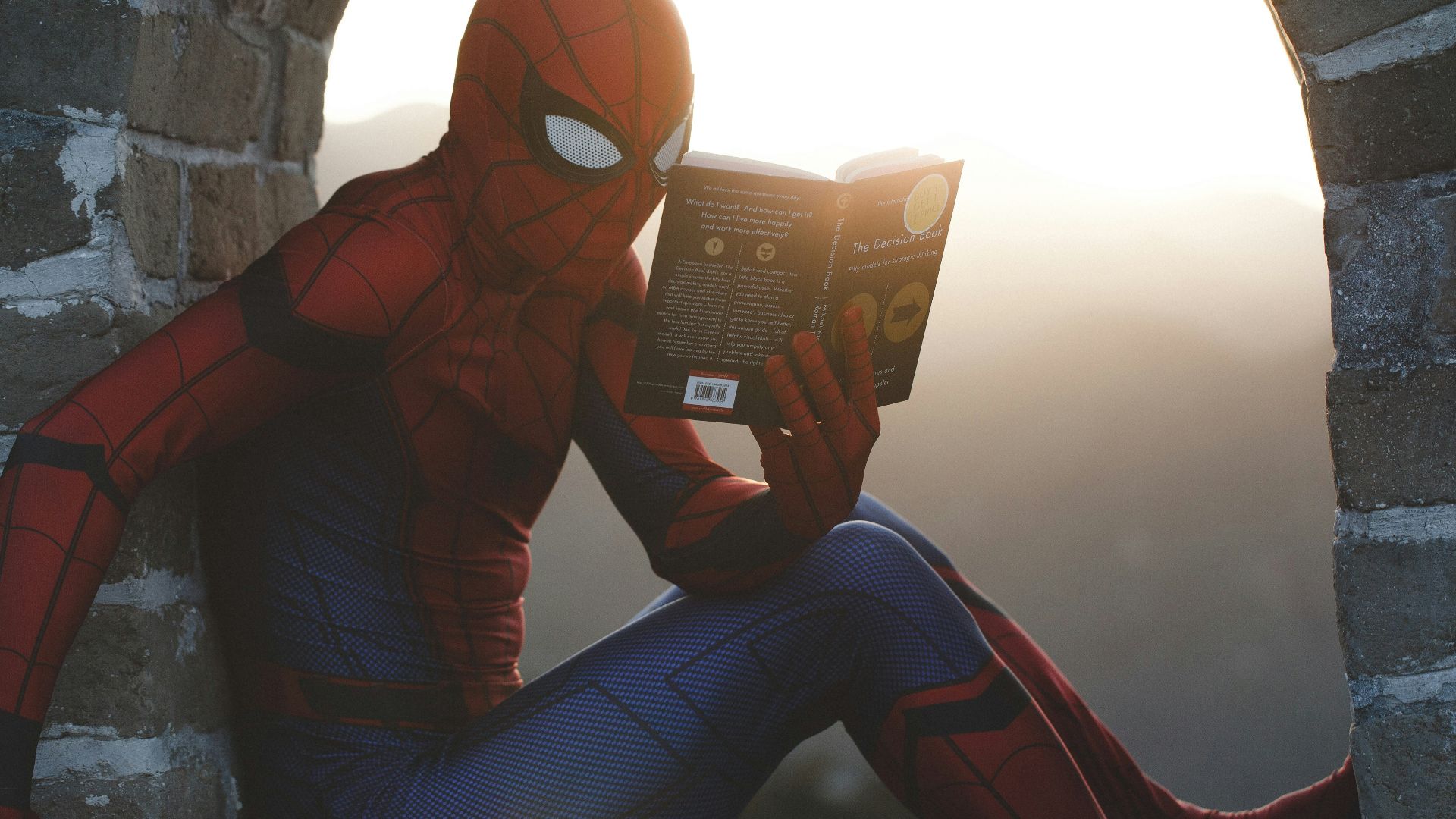Spider-Man leaning on concrete brick while reading book