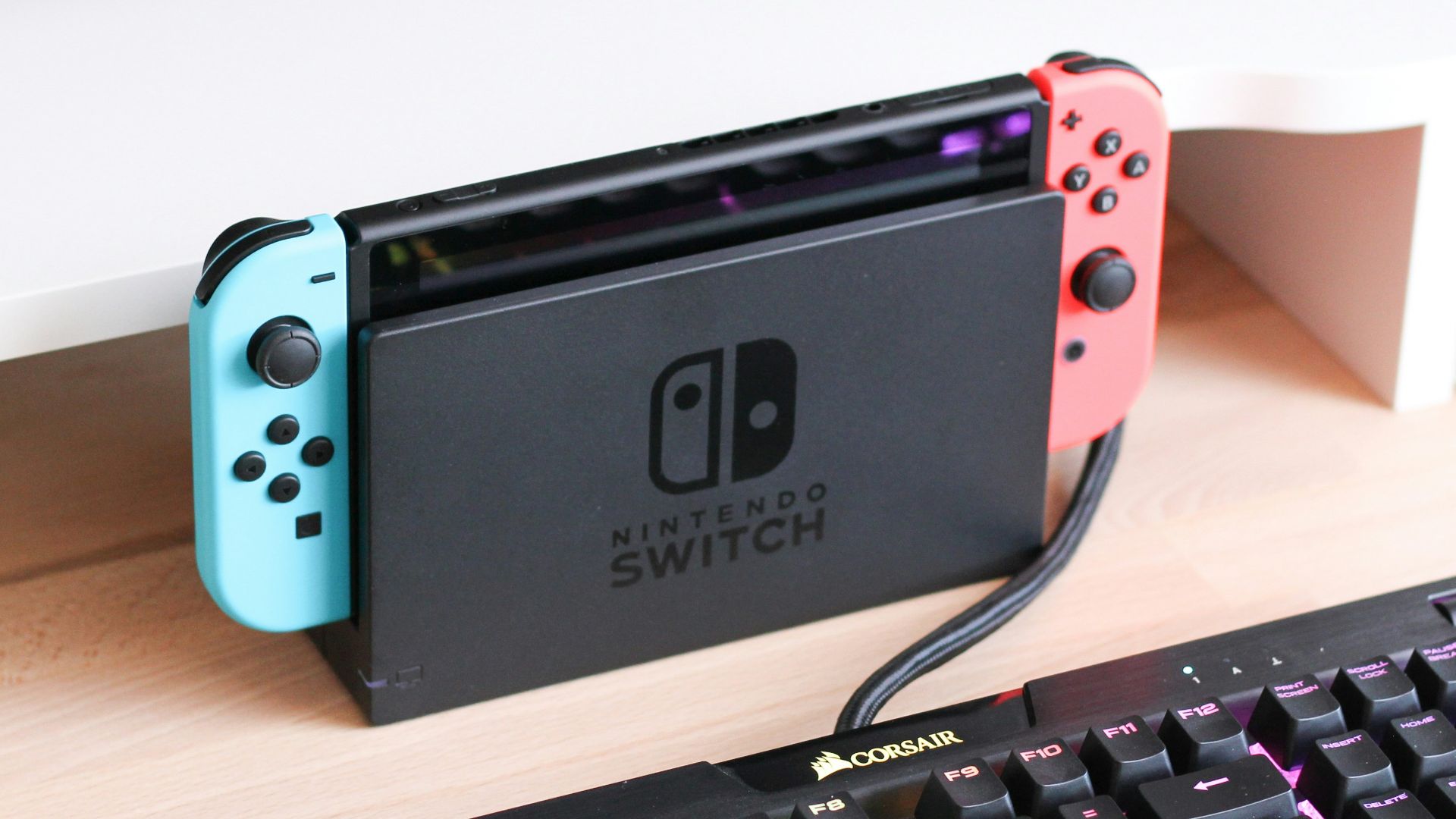 a nintendo switch sitting on a desk next to a keyboard