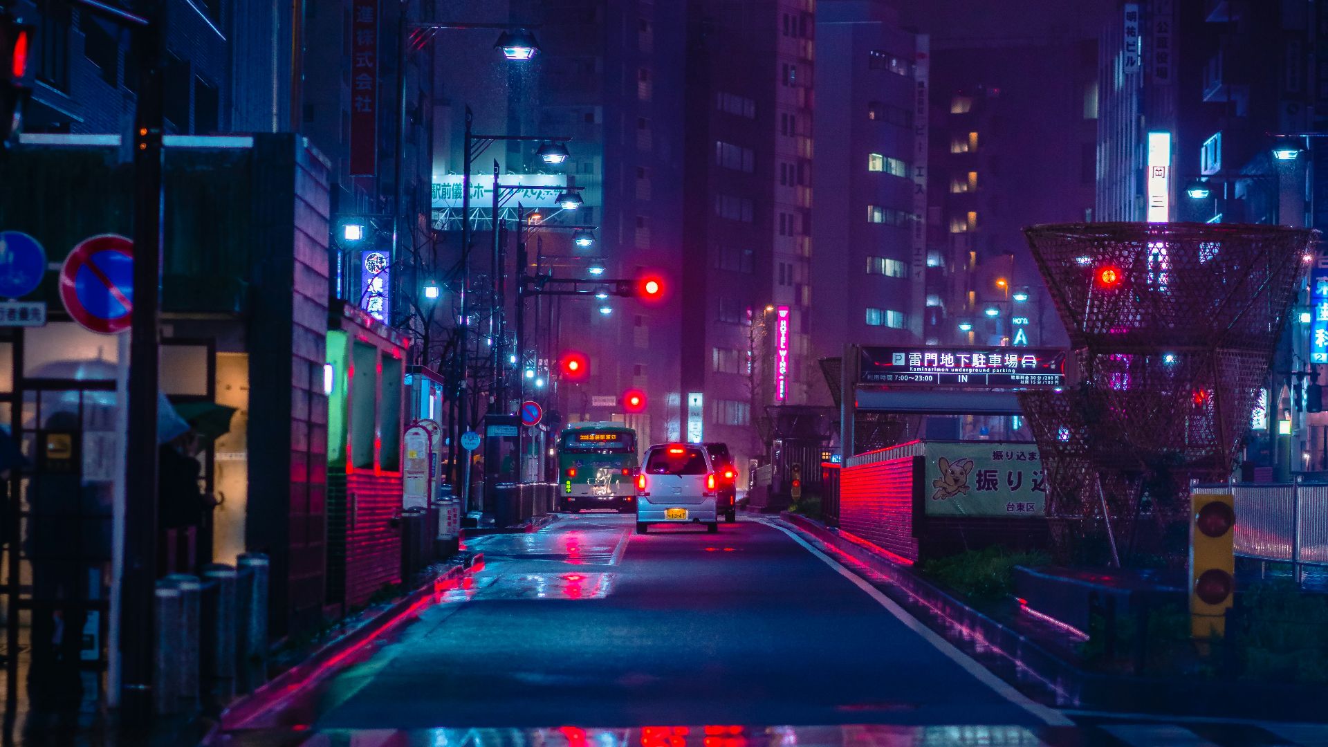 cars on road between high rise buildings during night time