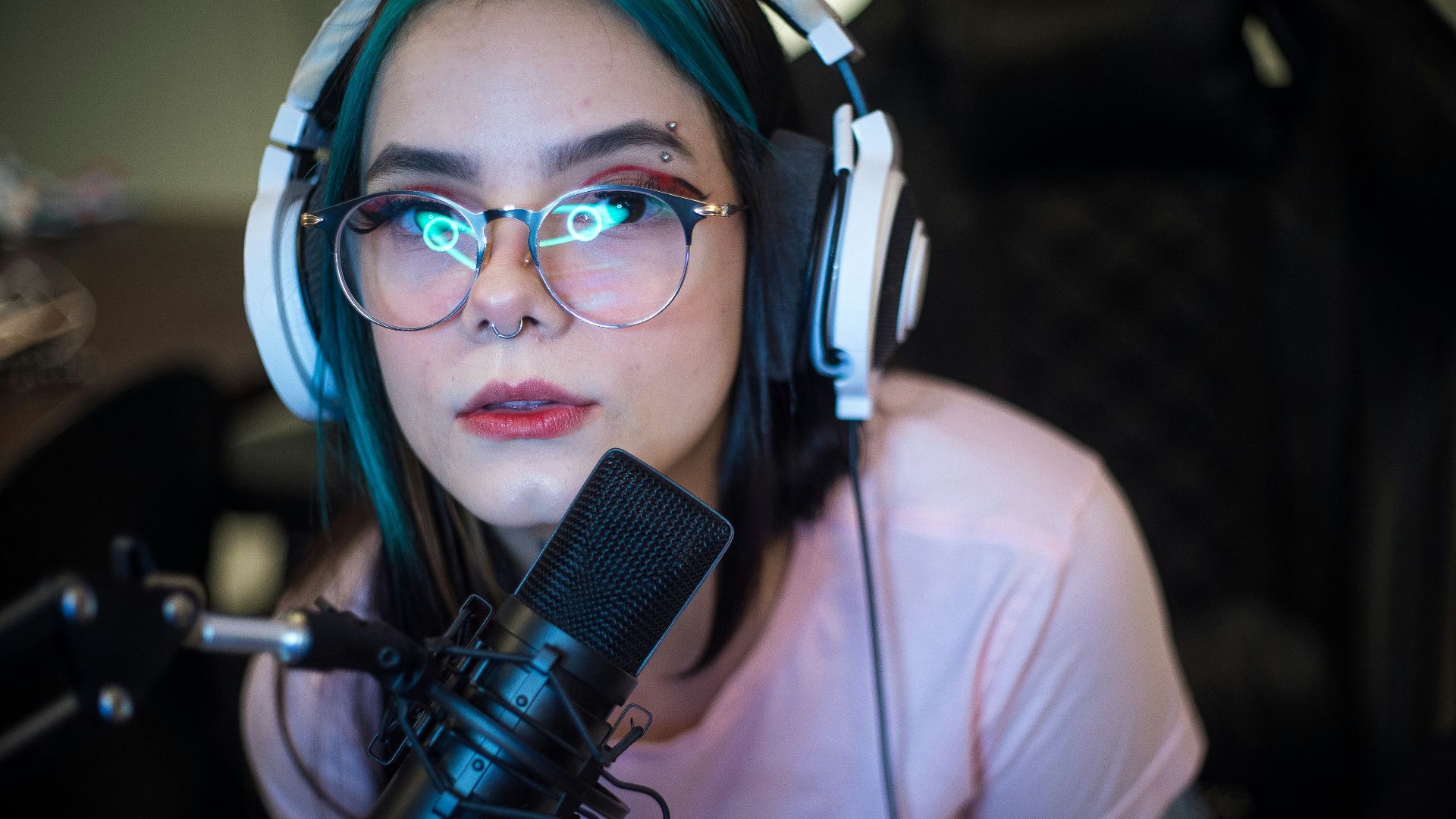 woman in white shirt wearing blue headphones holding black microphone