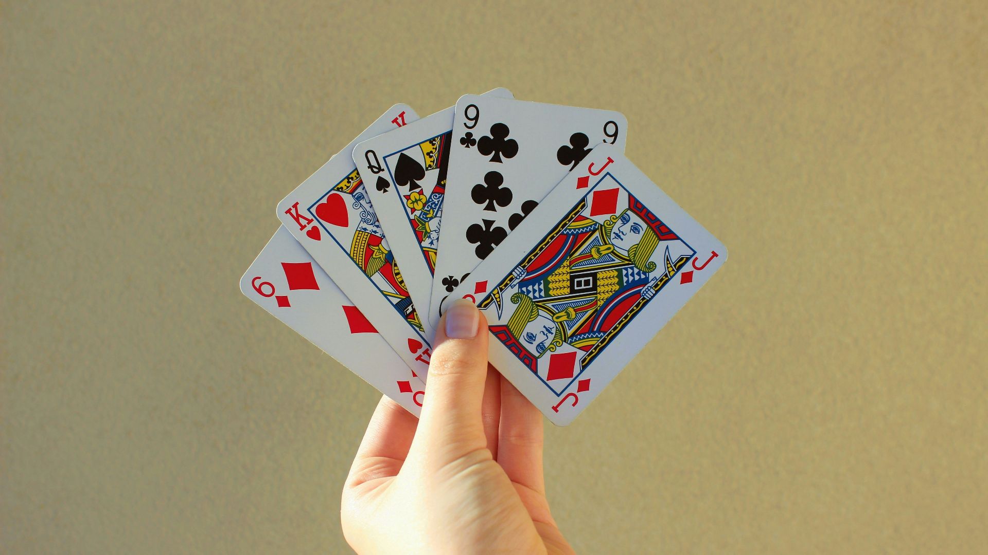 a person holding four playing cards in their hand
