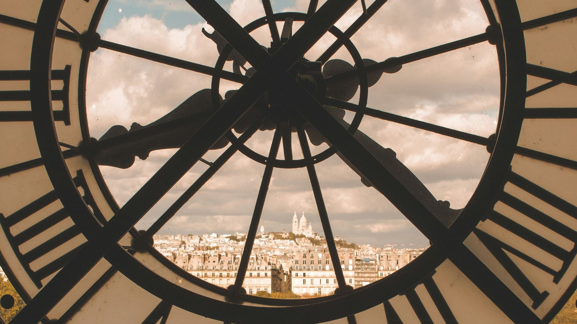 a large clock with roman numerals and a city in the background