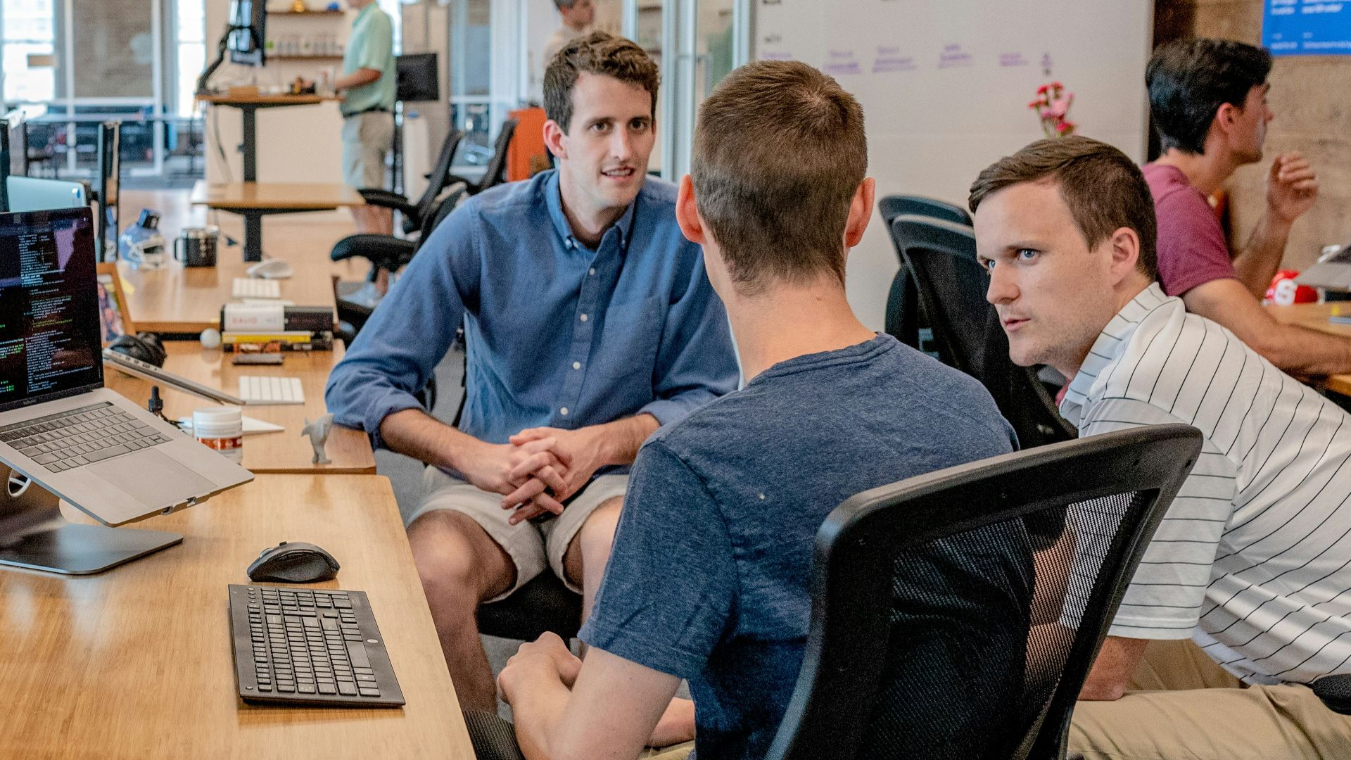 three men sitting on chair beside tables
