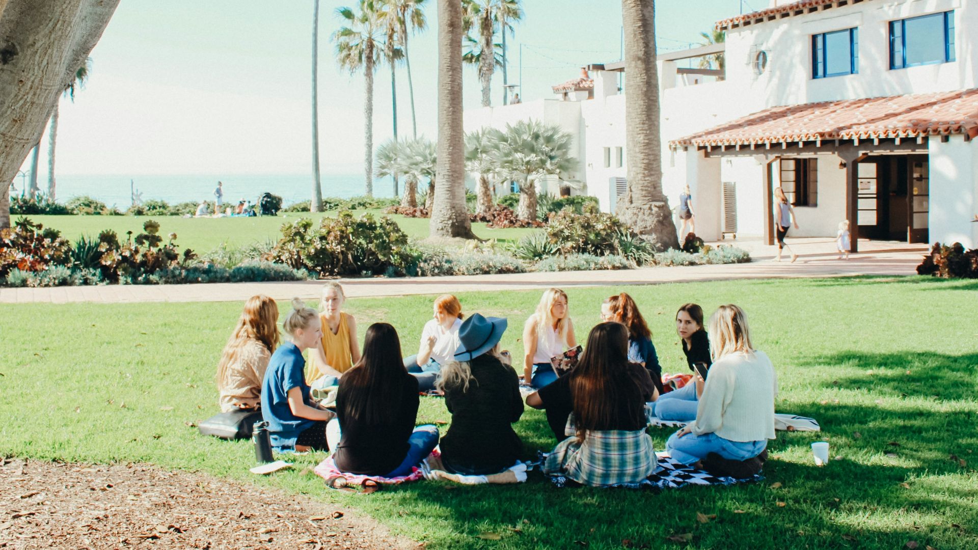 people sitting on ground while forming round during daytime