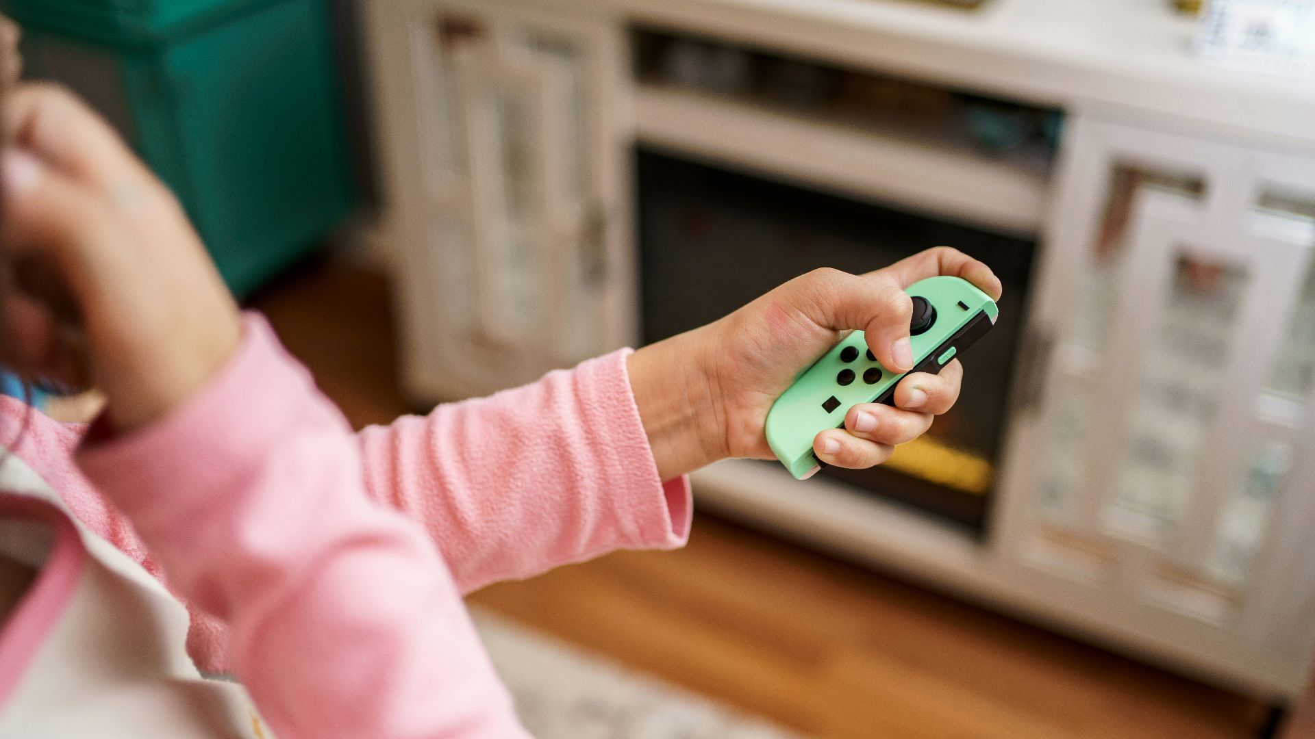 child in pink long sleeve shirt holding green and white plastic toy