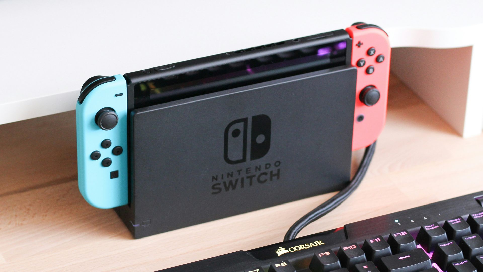a nintendo switch sitting on a desk next to a keyboard