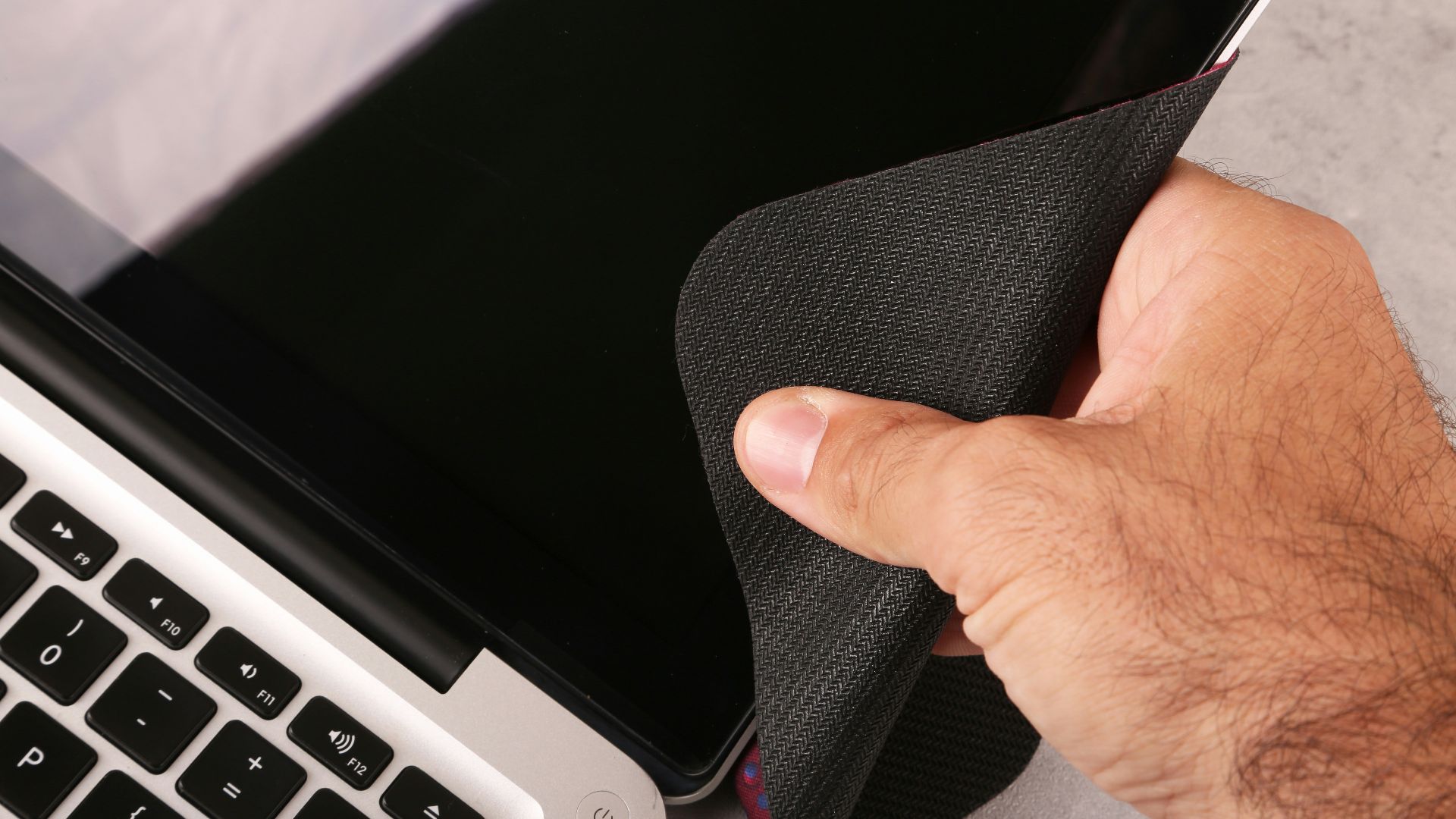 a hand holding a cloth over a laptop