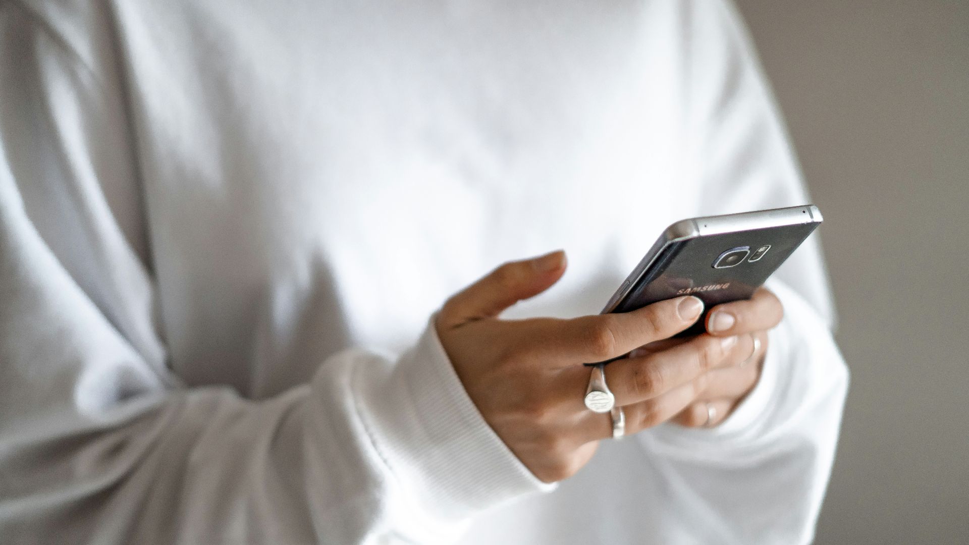 person in white long sleeve shirt holding black smartphone