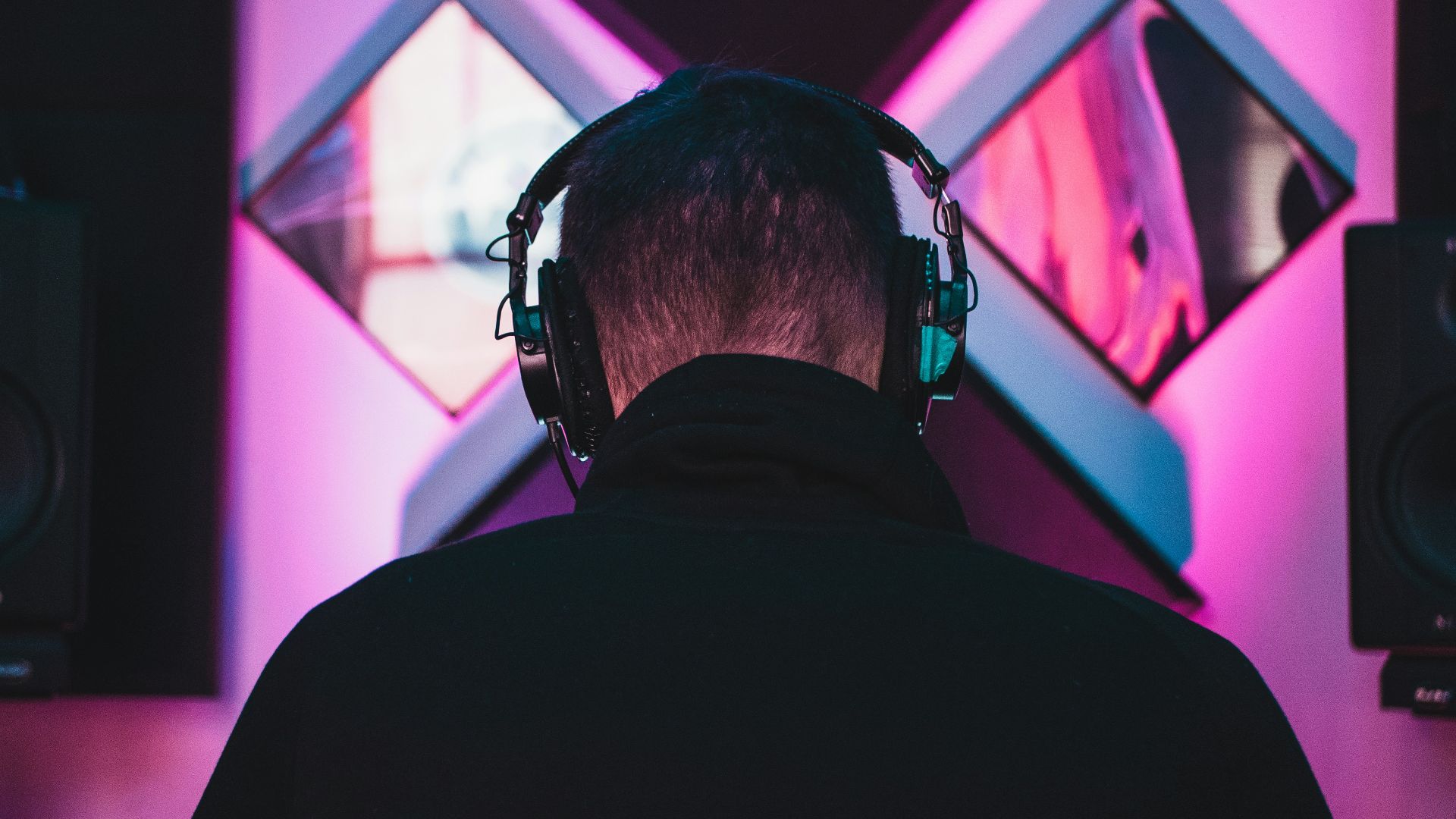 man wearing black headphones near two PA speakers