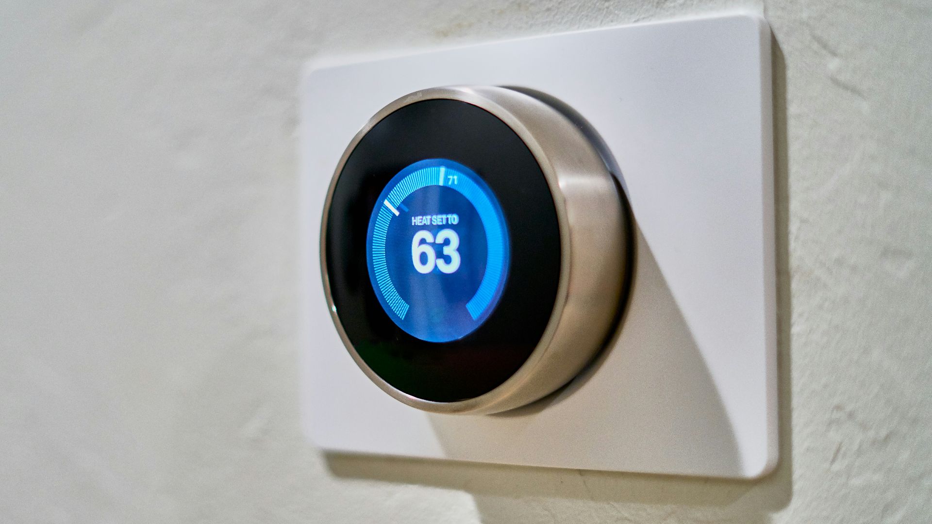 gray Nest thermostat displaying at 63