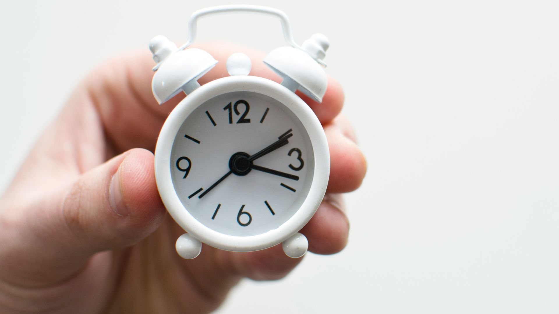 person holding white mini bell alarmclock