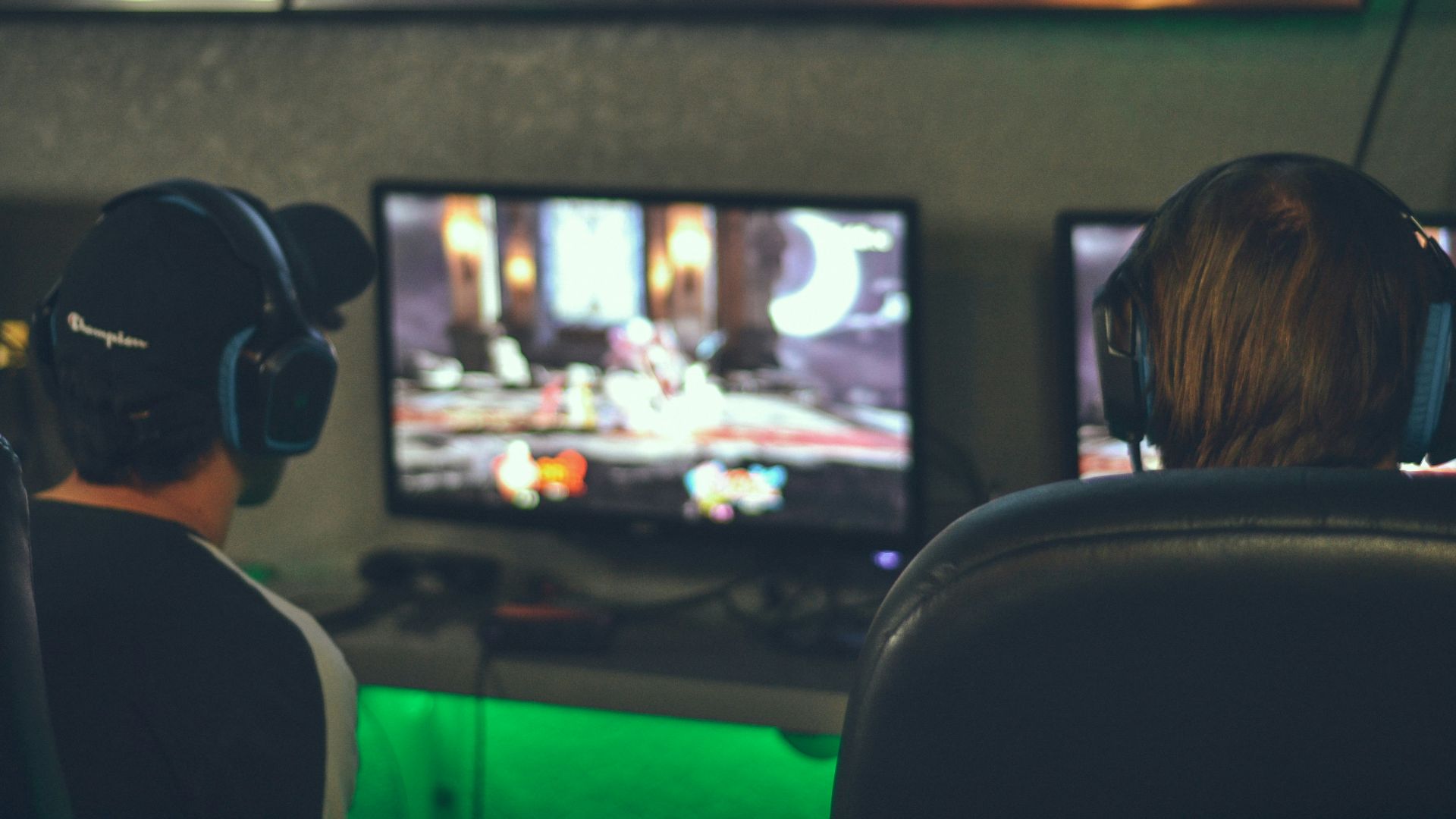 selective focus photography of two persons playing game in front of monitors