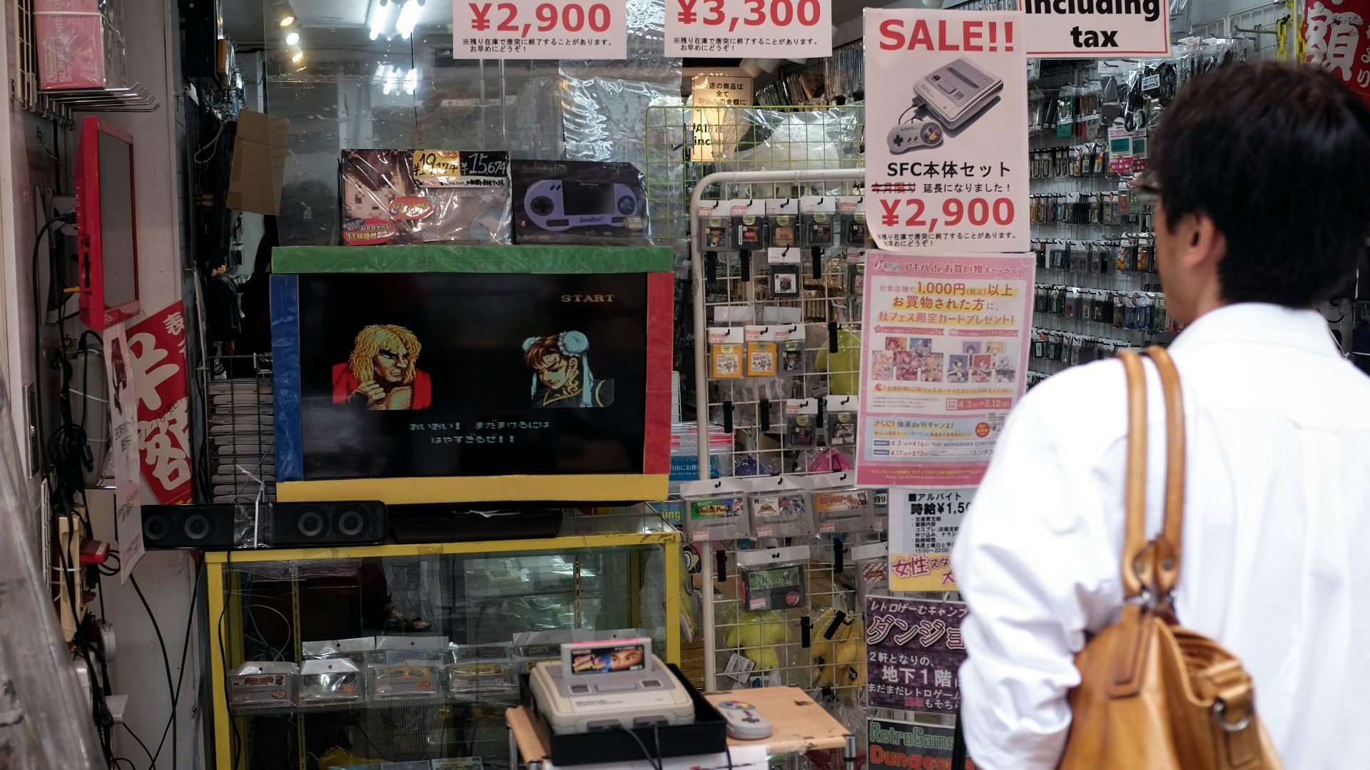 man in white dress shirt and brown pants standing near glass shelf