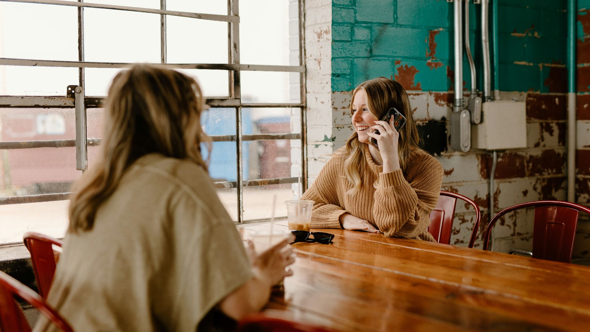 a woman sitting at a table talking on a cell phone
