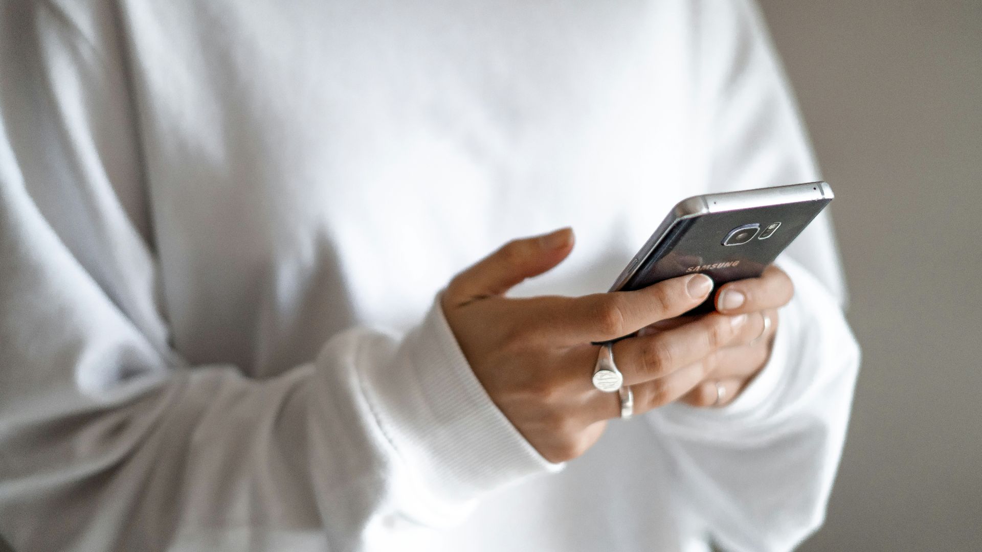 person in white long sleeve shirt holding black smartphone
