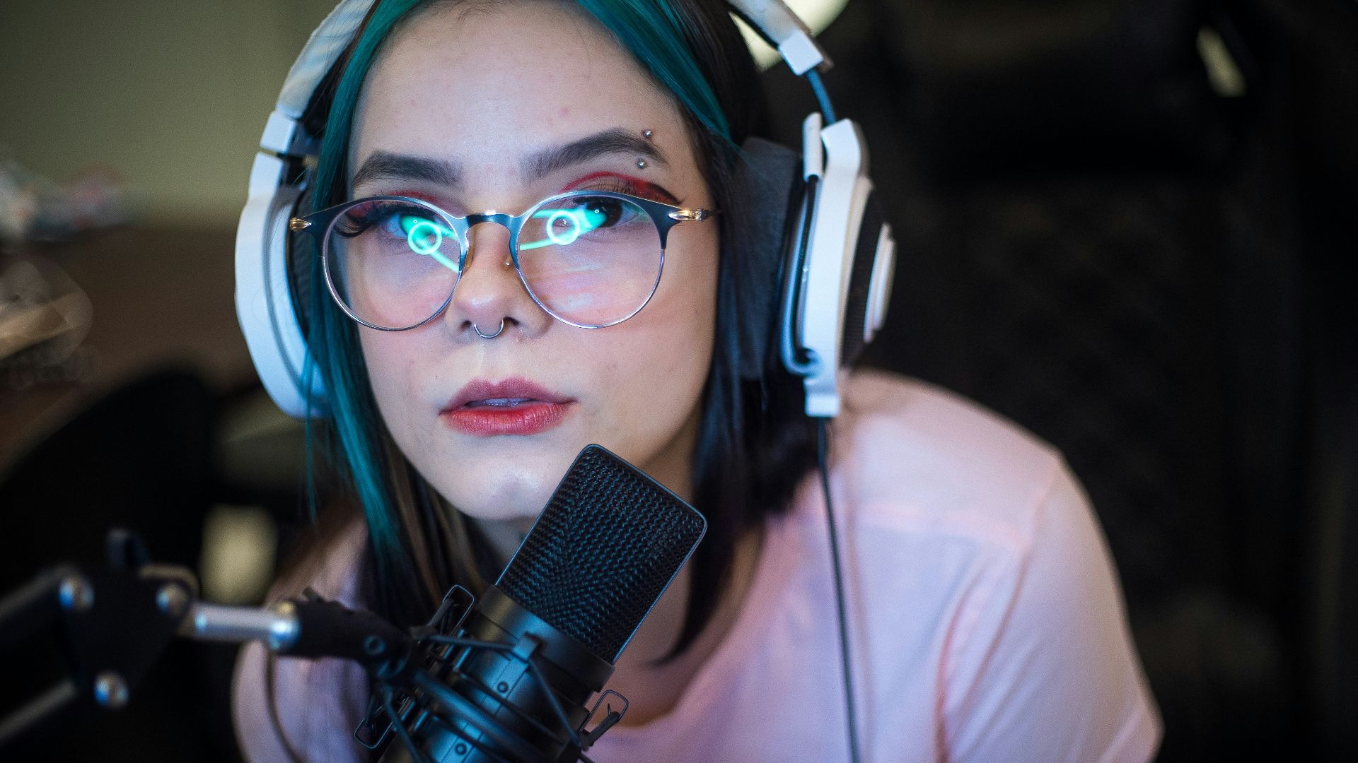 woman in white shirt wearing blue headphones holding black microphone