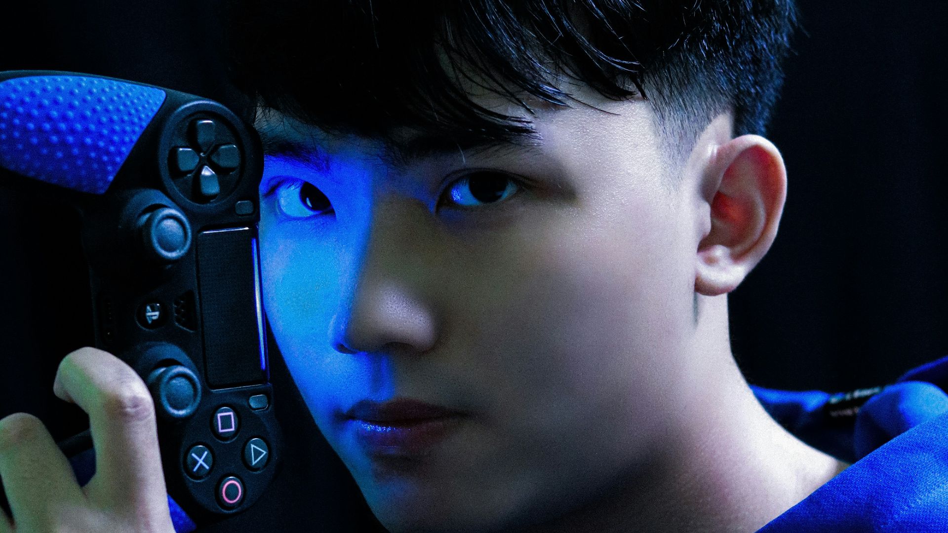 boy in blue long sleeve shirt holding black game controller