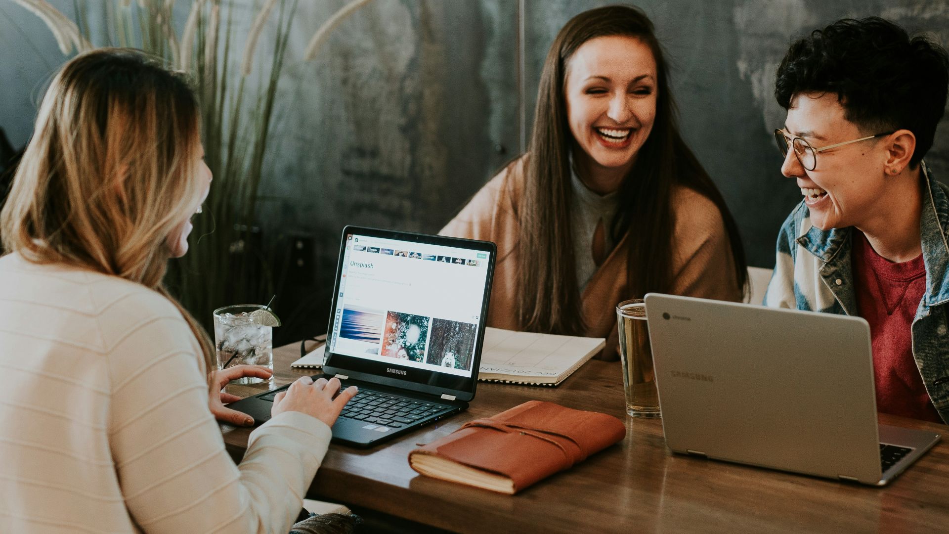 three people sitting in front of table laughing together