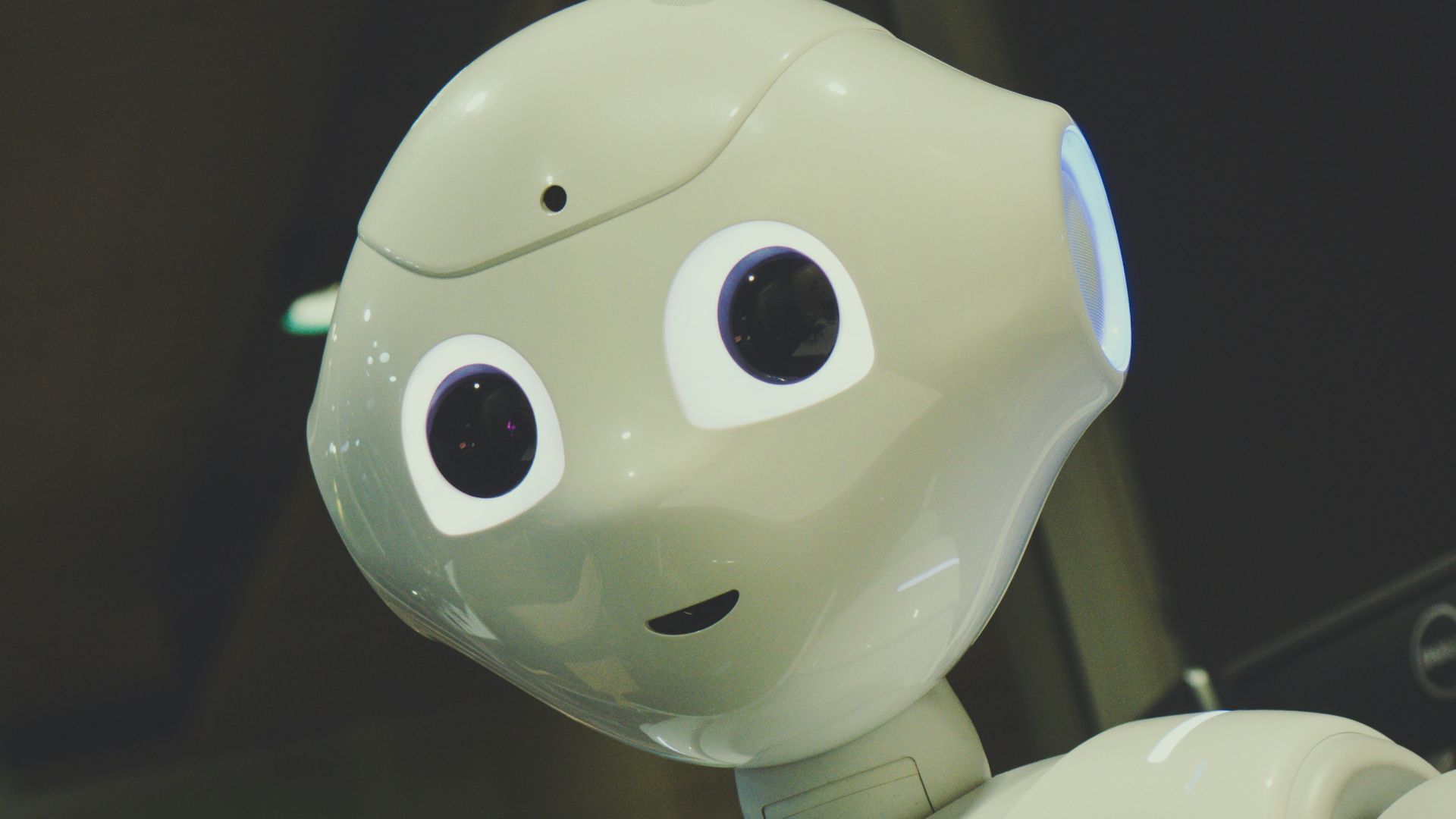 white robot toy holding black tablet