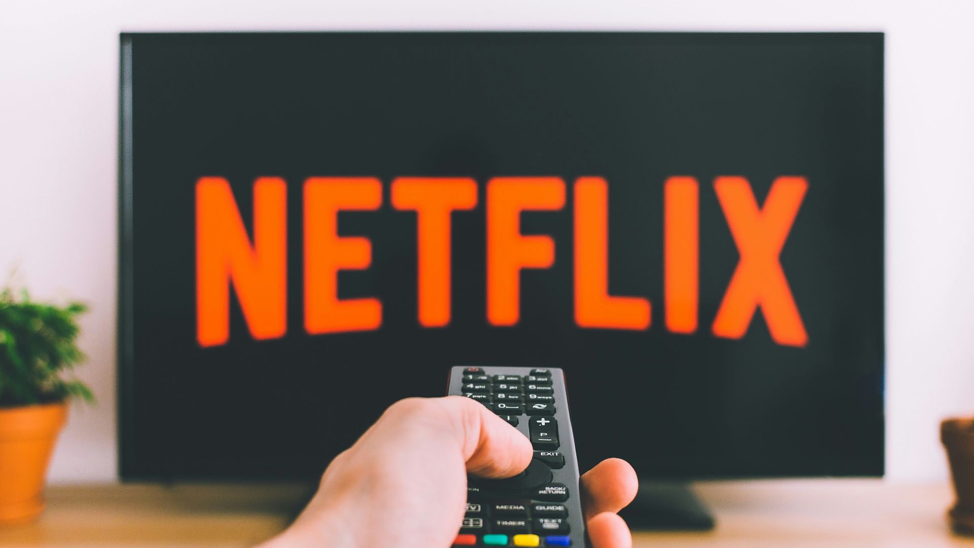 person holding remote pointing at TV
