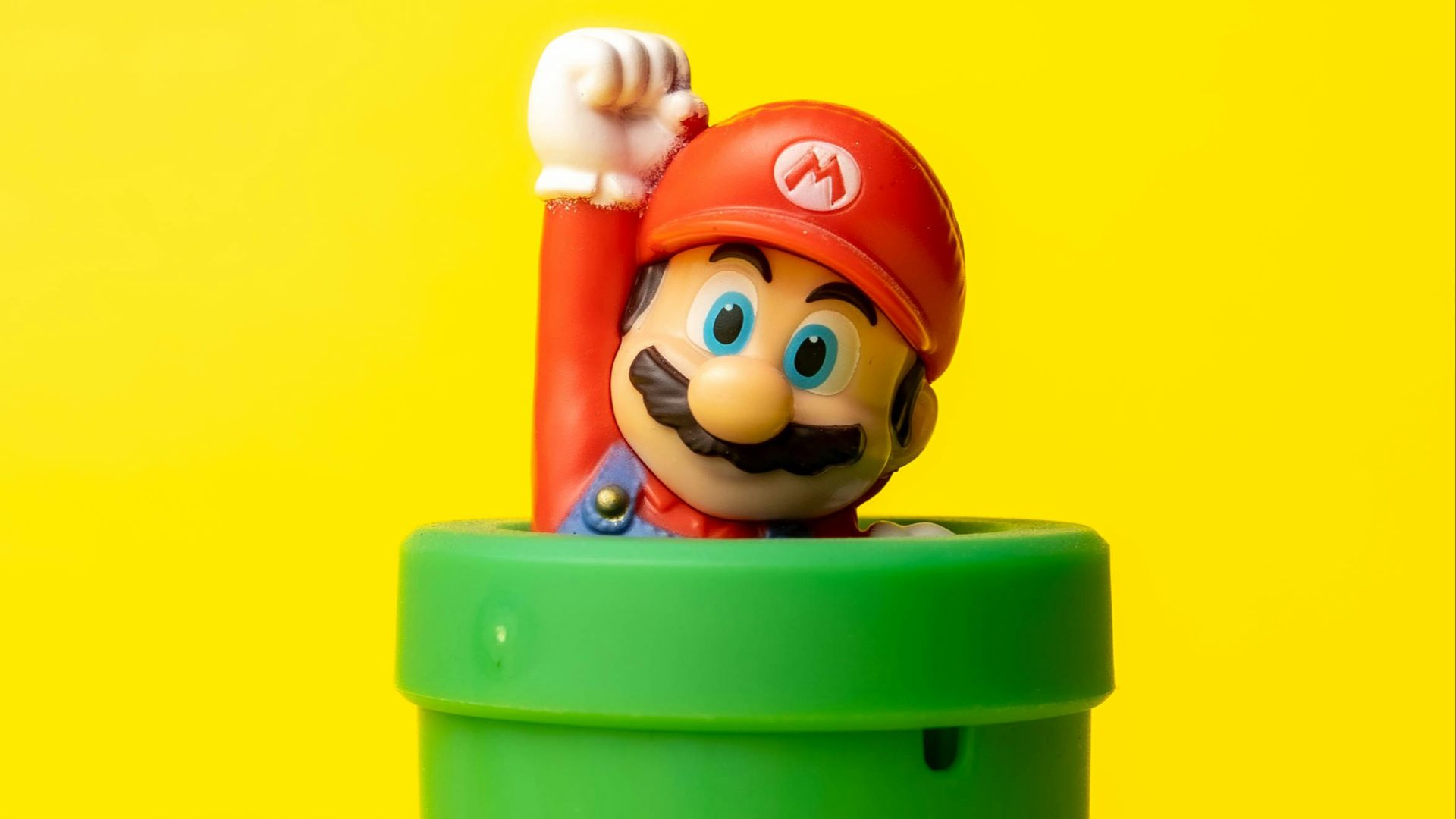a toy mario in a green container on a yellow background