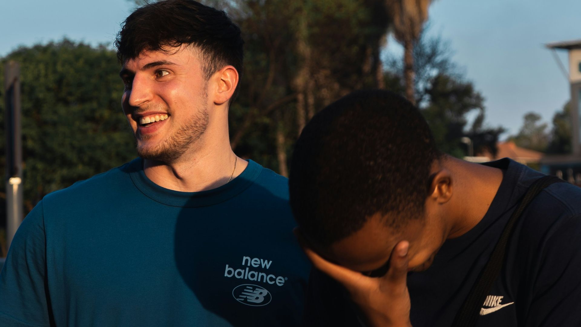 two men standing next to each other in a parking lot