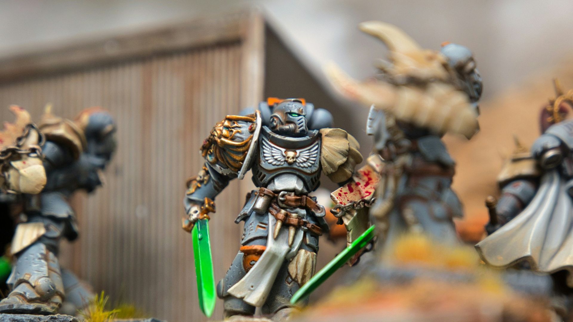 A group of warhammers on a table with a building in the background