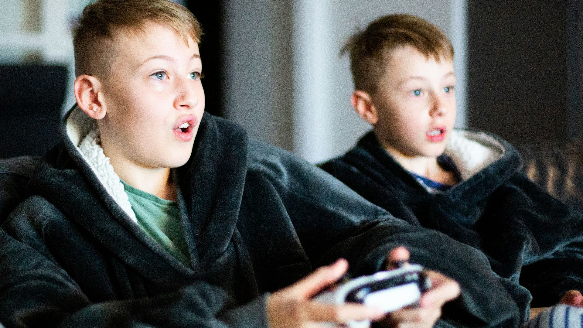 two young boys sitting on a couch playing a video game