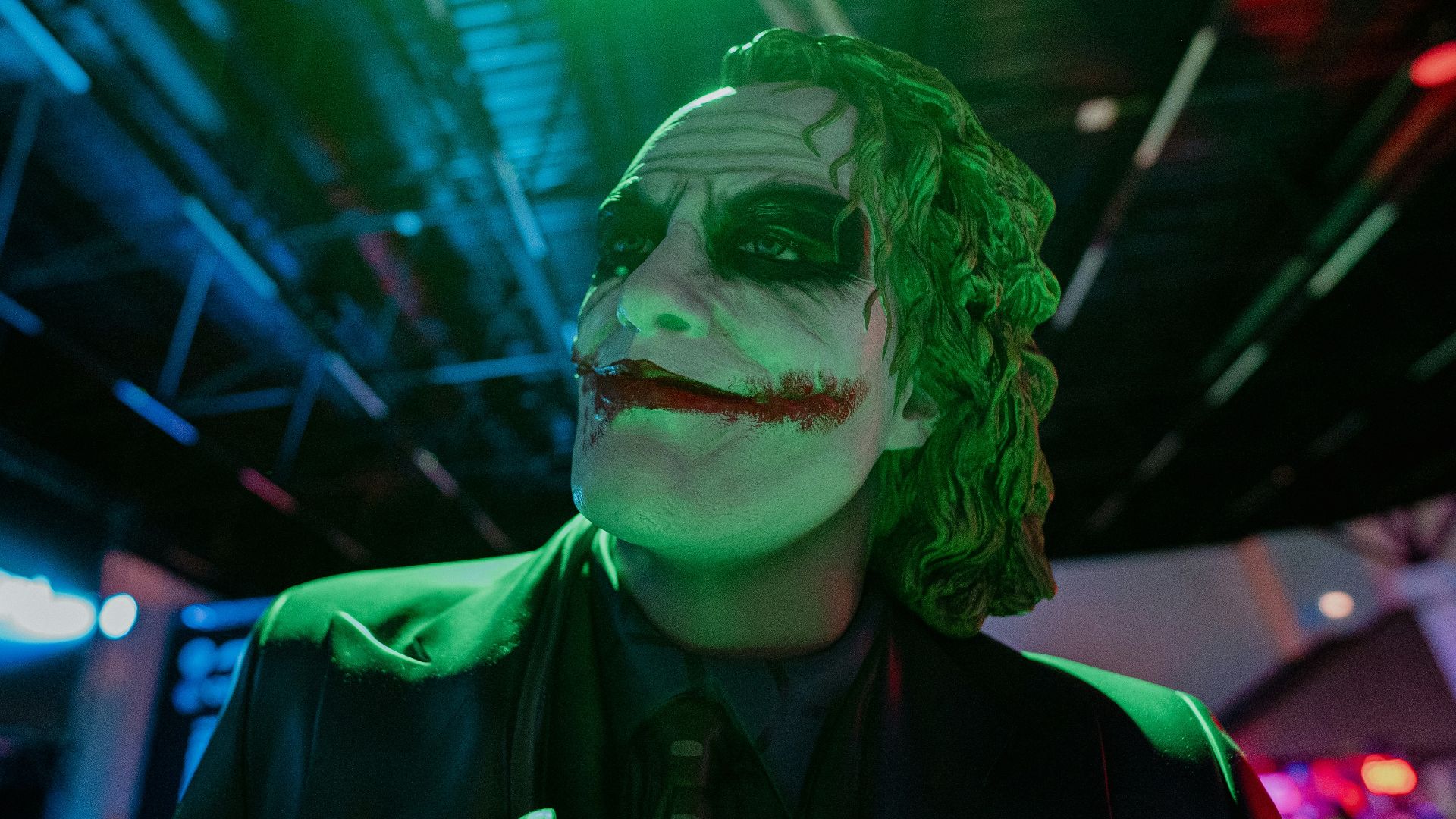 The joker smiles in the green and blue light.