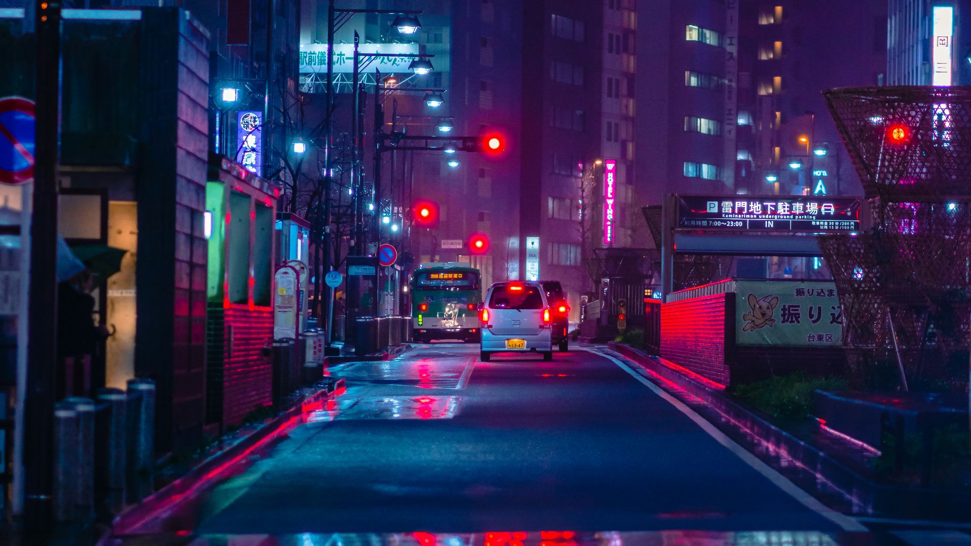 cars on road between high rise buildings during night time