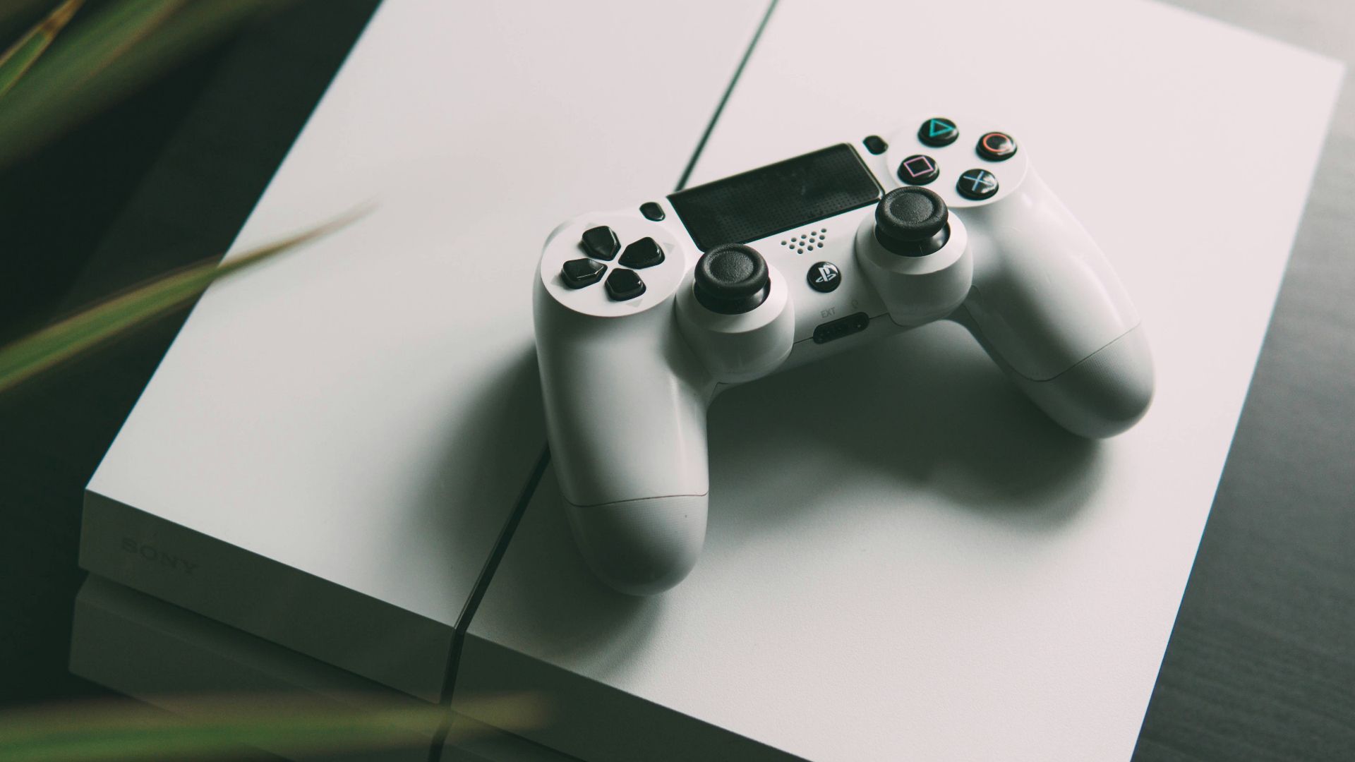 selective focus photography of white Sony PS4 console with wireless controller
