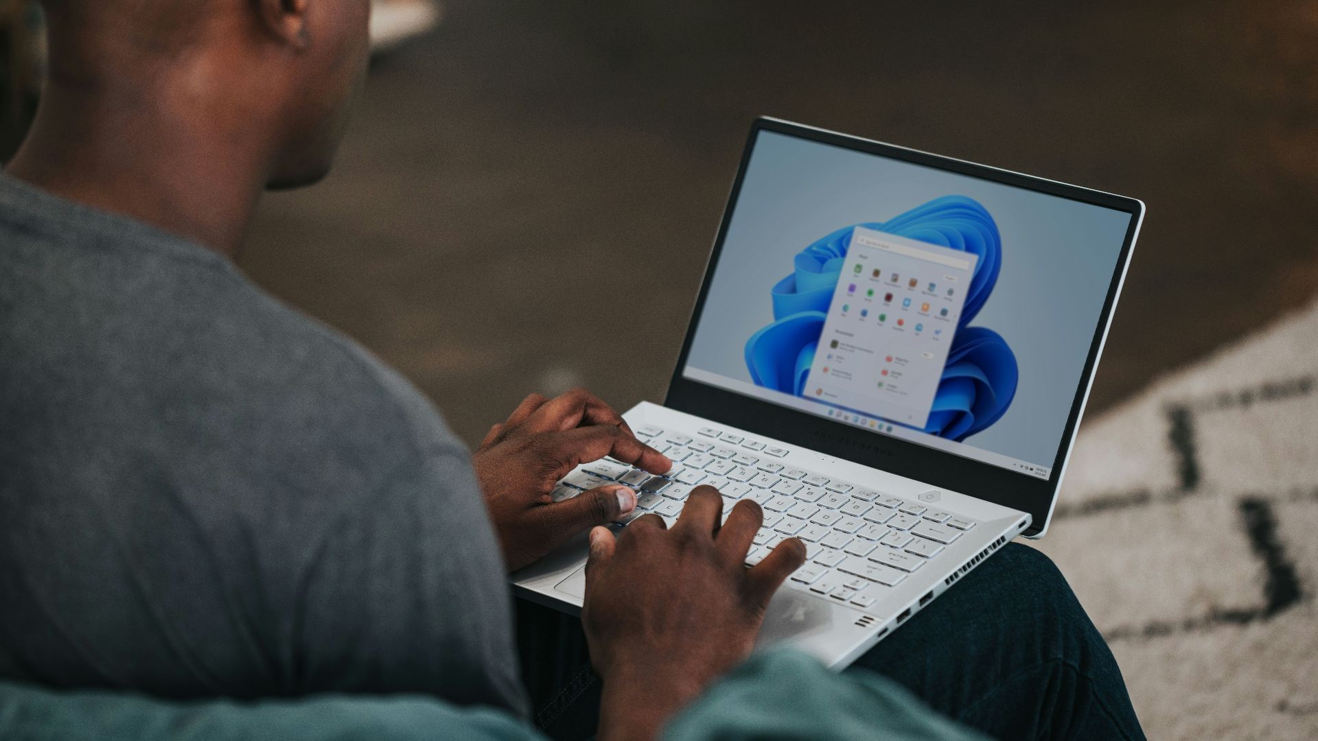man in gray long sleeve shirt using Windows 11 computer